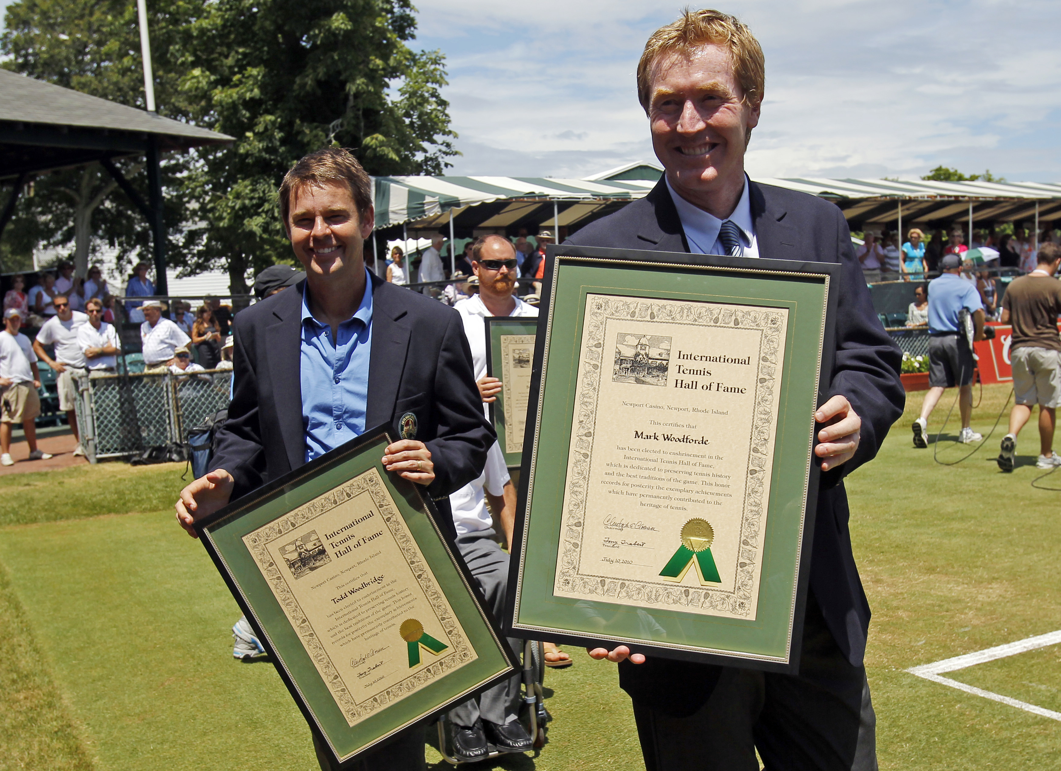 Doubles partners Mark Woodforde and Todd Woodbridge of Australia carry their plaques around center court after being inducted into the International Tennis Hall of Fame in Newport