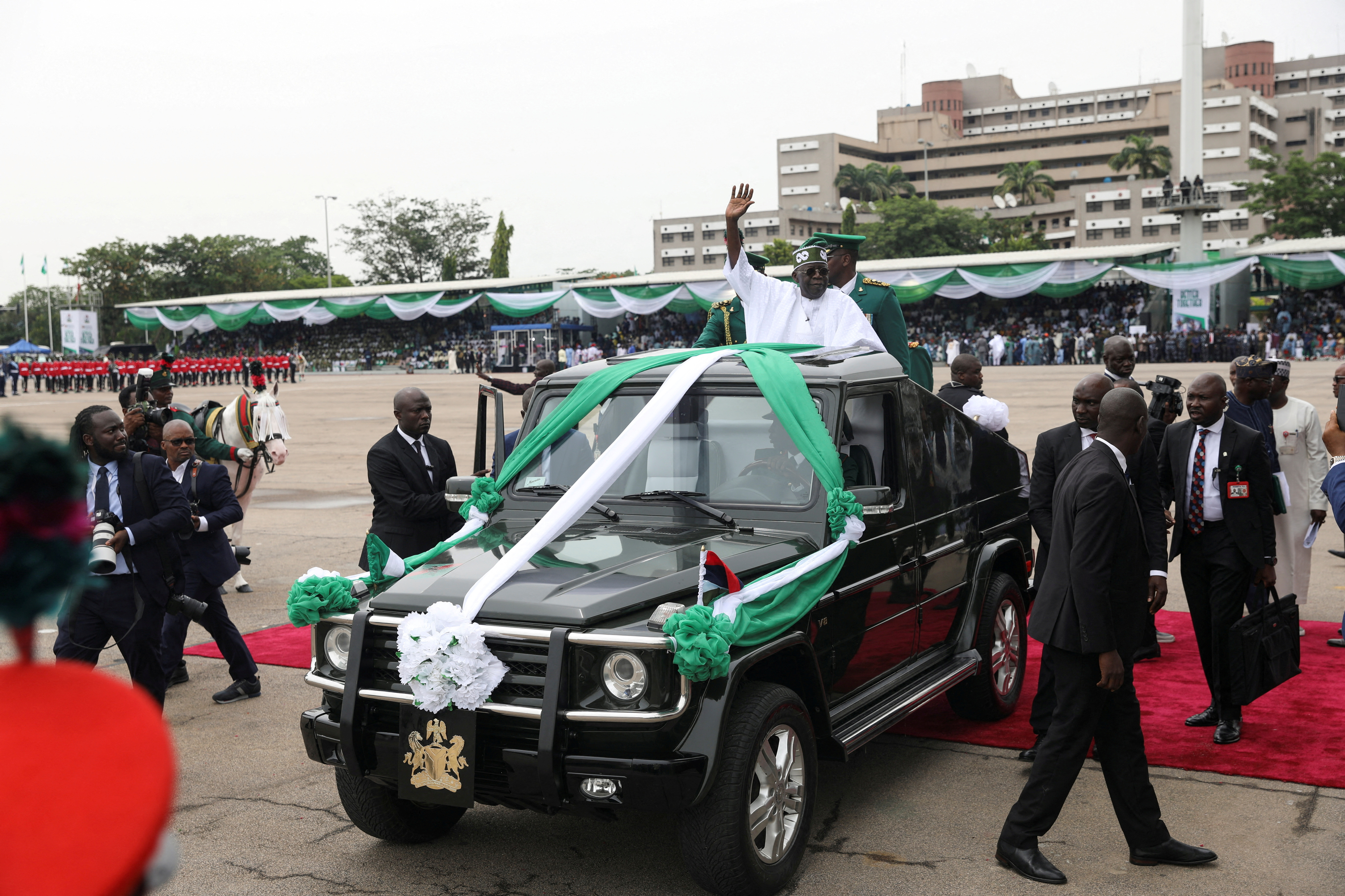 Nigeria's President Bola Tinubu waves to the crowd as he takes a traditional drive on a top of a ceremonial vehicle after his swearing-in ceremony in Abuja