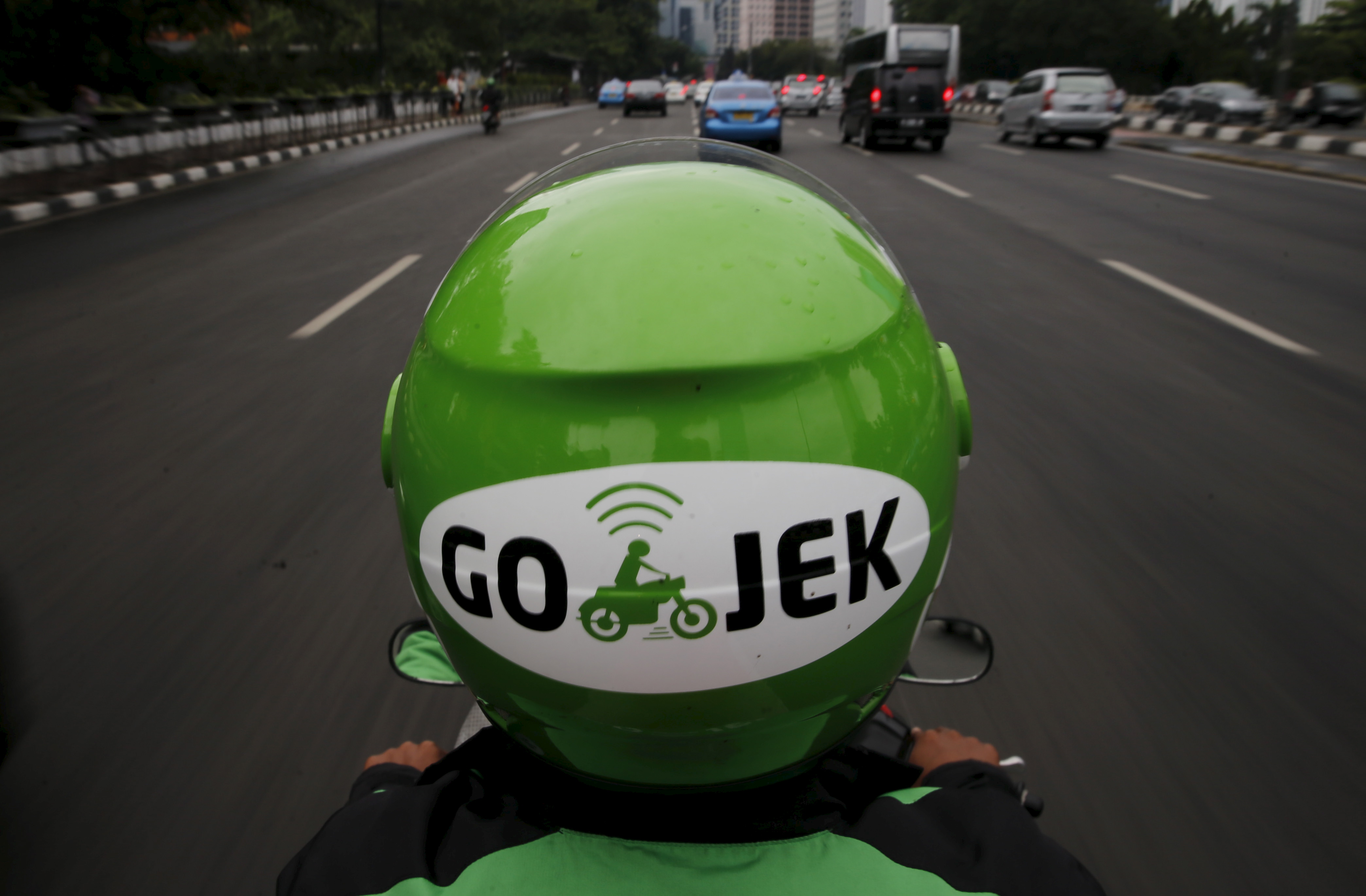 A Gojek driver rides his motorcycle through a business district street in Jakarta, June 9, 2015. REUTERS/Beawiharta  