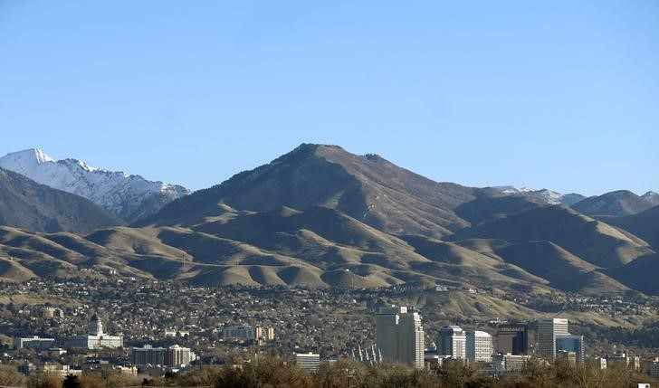 Mountains rise up behind the Salt Lake City skyline and the Utah State Capitol building