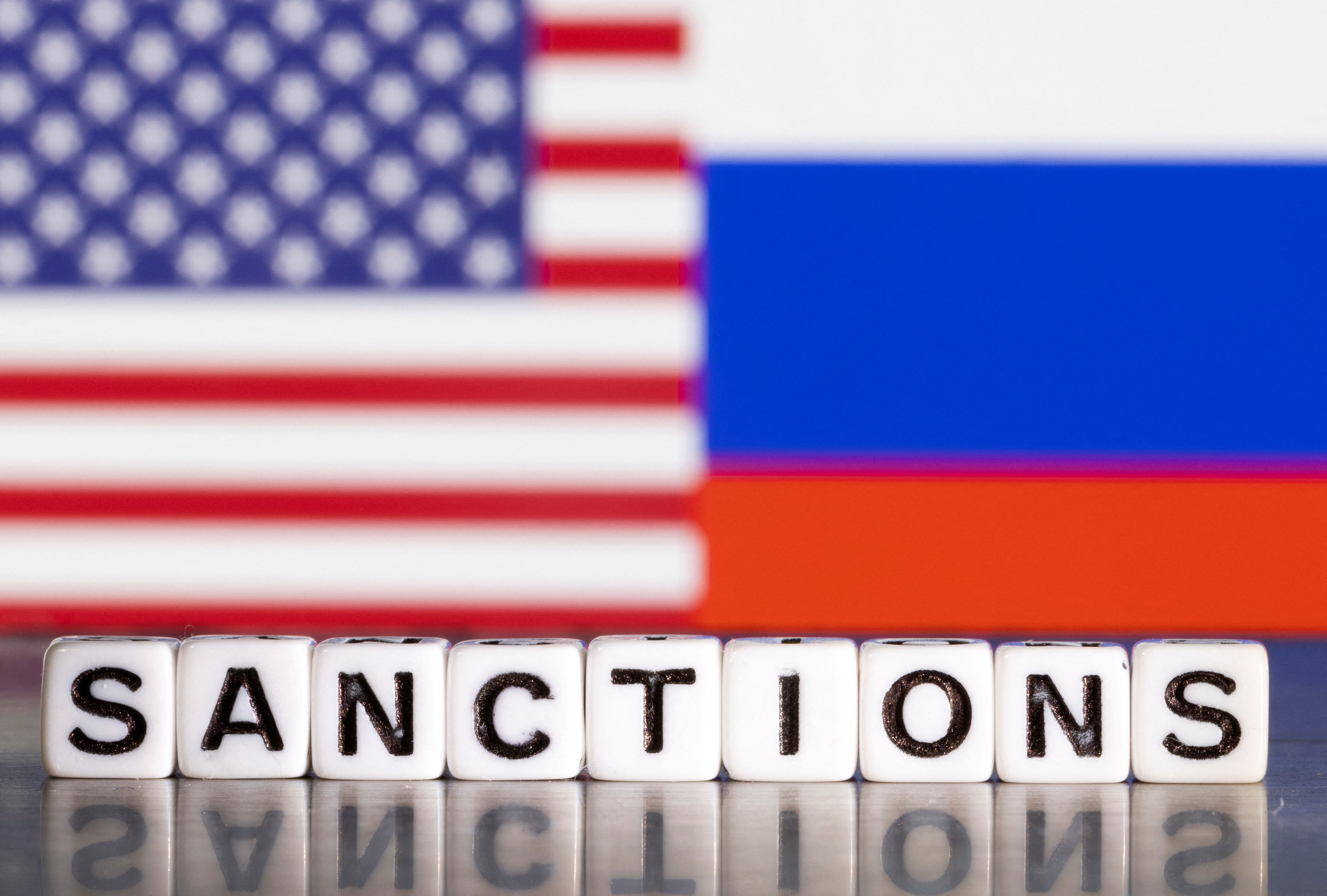 Illustration shows letters arranged to read "Sanctions" in front of flag colors of U.S. and Russia