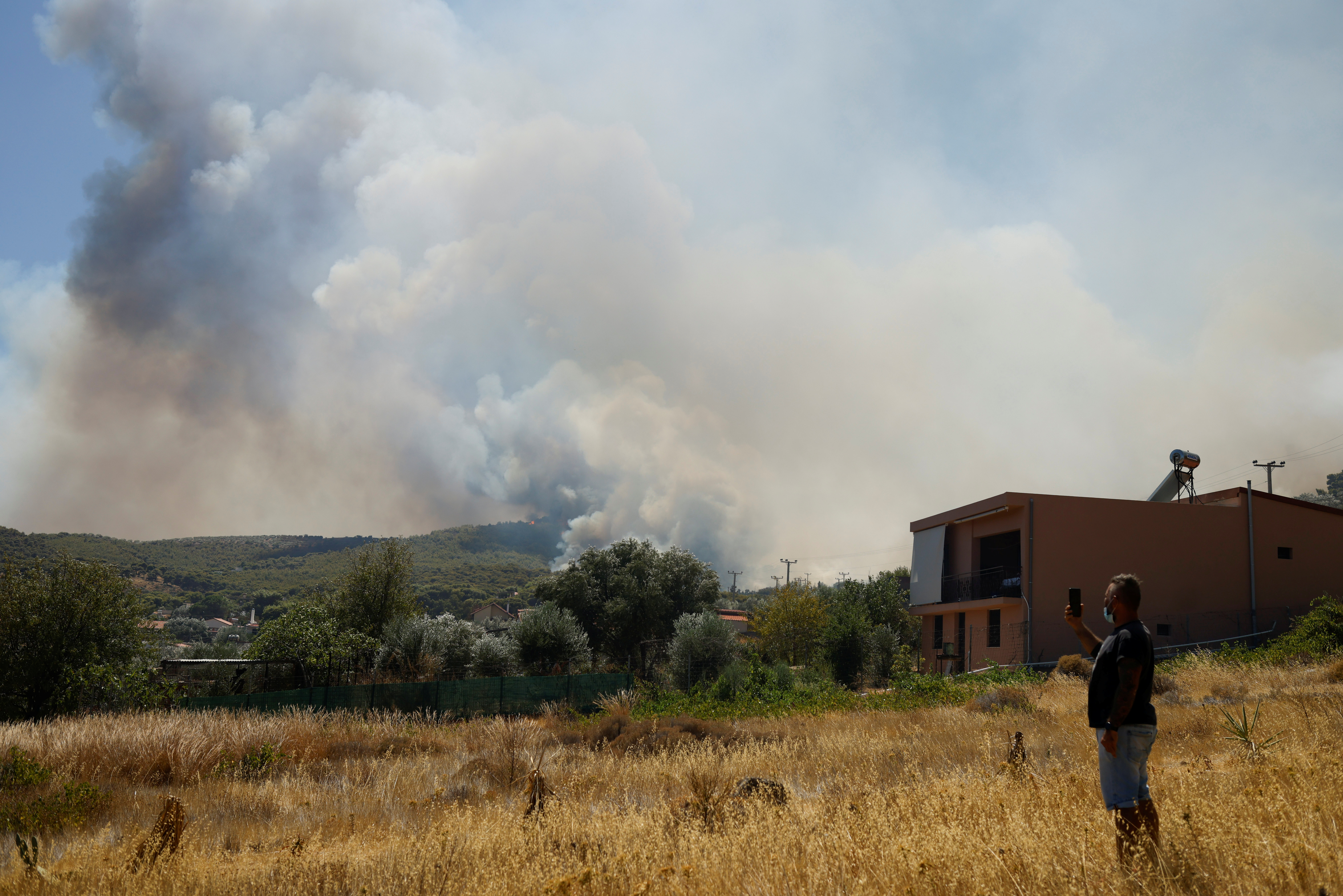 A man takes a picture of a wildfire burning in the village of Markati, near Athens, Greece, August 16, 2021. REUTERS/Alkis Konstantinidis