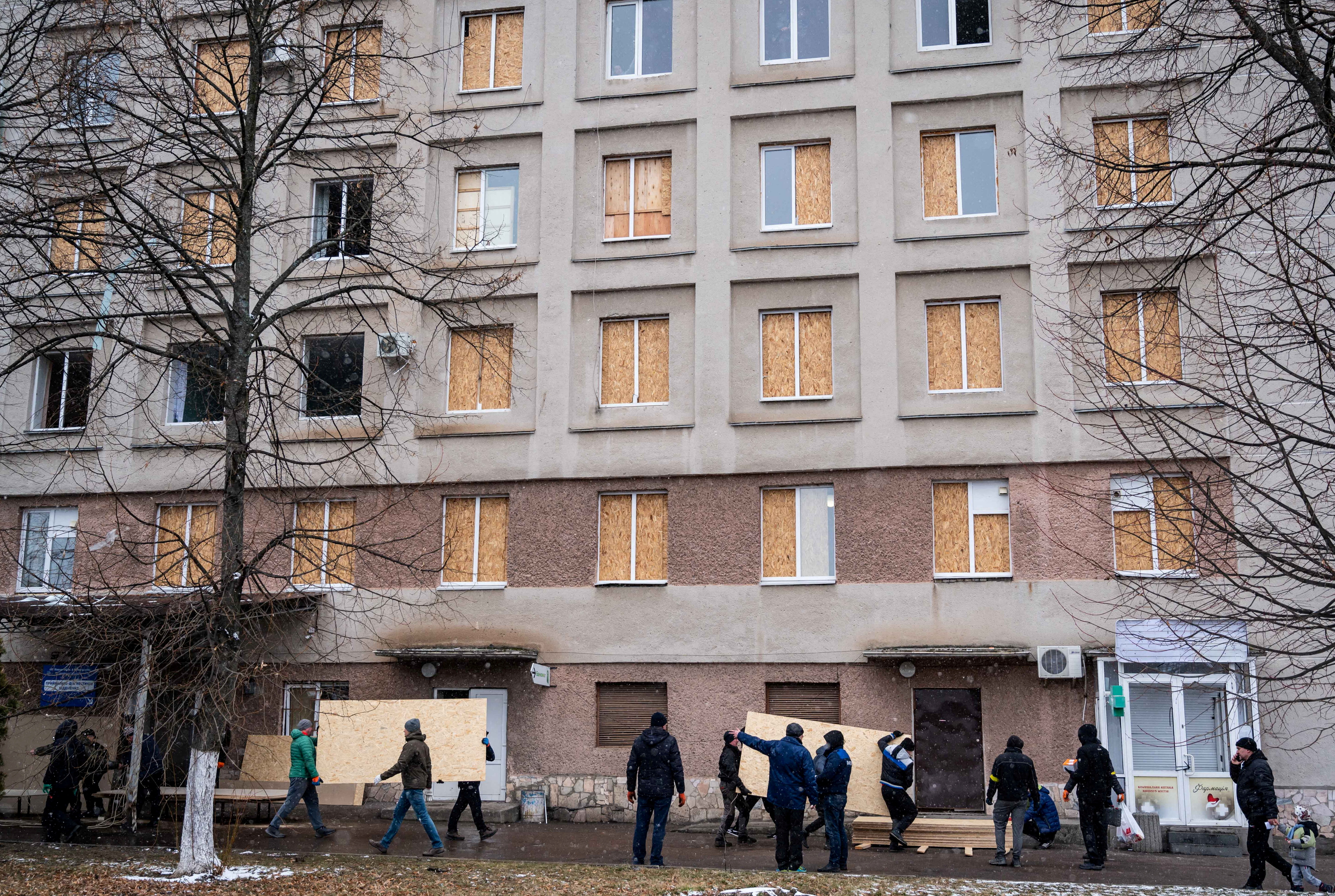 Men use sheets of plywood to cover windows of a hospital following shelling in Zhytomyr