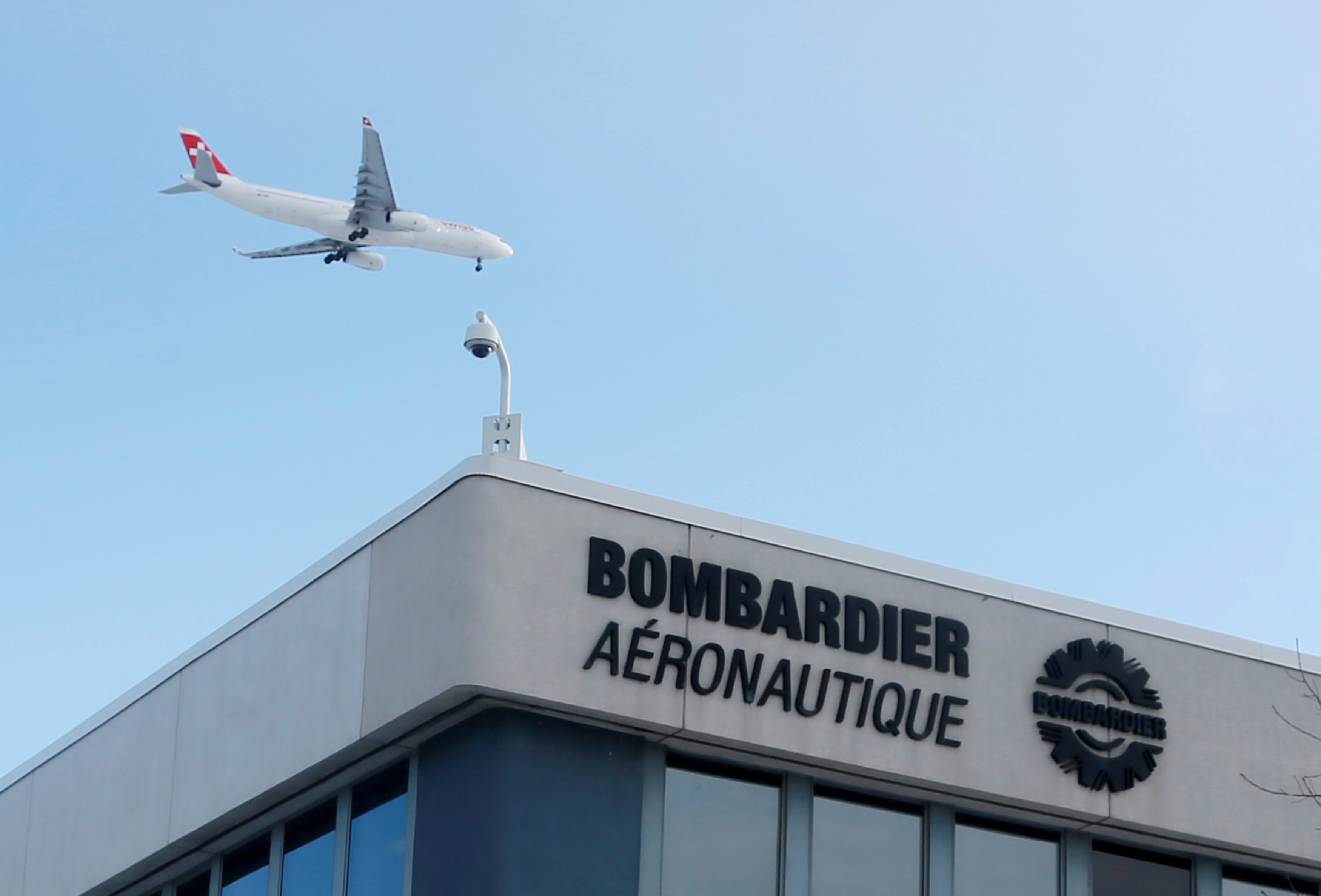 A plane flies over a Bombardier plant in Montreal