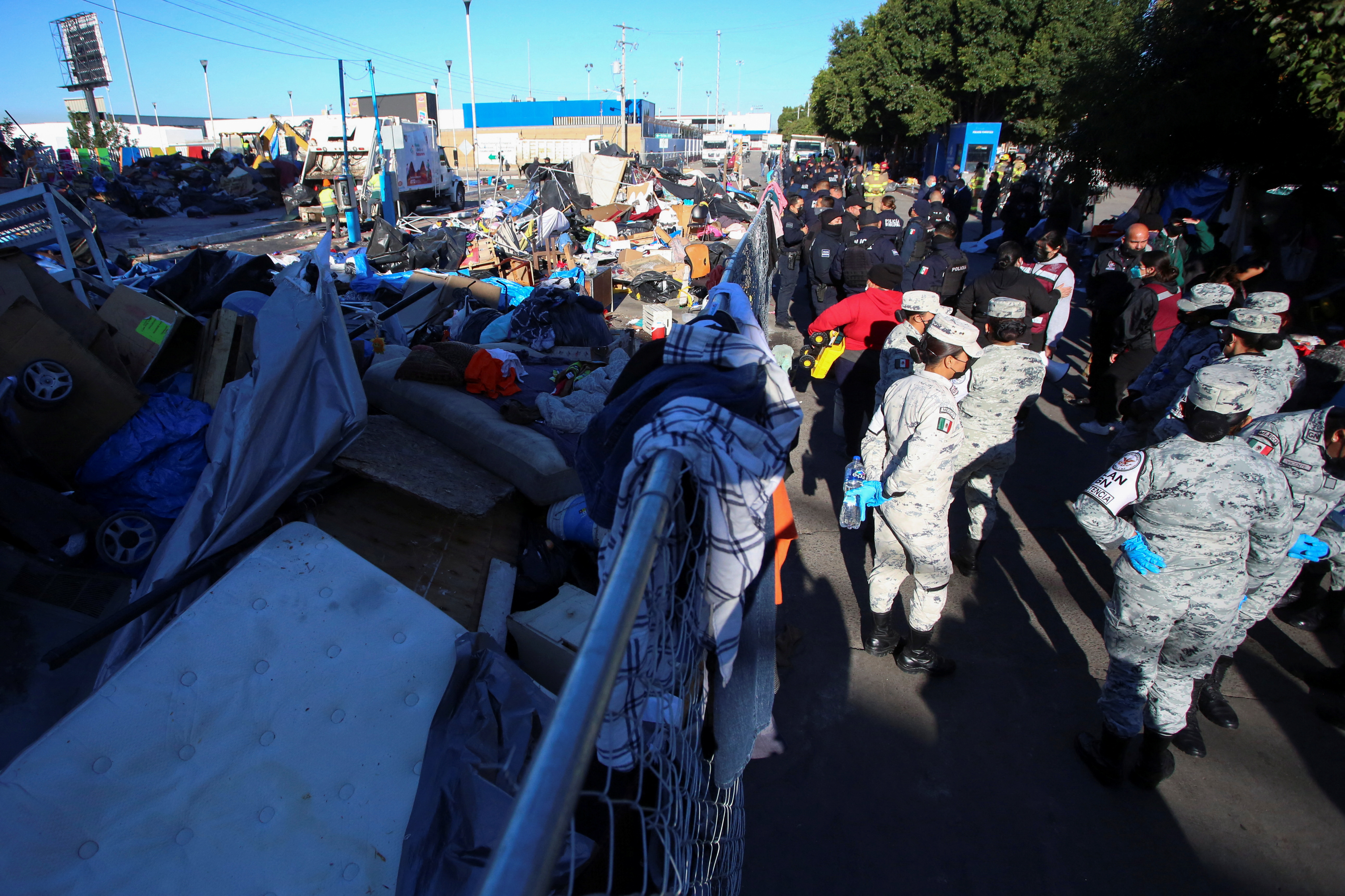 Soldiers keep watch next to belongings of migrants after Mexican authorities cleared a makeshift camp, where hundreds of migrants heading towards the U.S. border were staying, at the El Chaparral border crossing in Tijuana, Mexico, February 6, 2022. REUTERS/Jorge Duenes