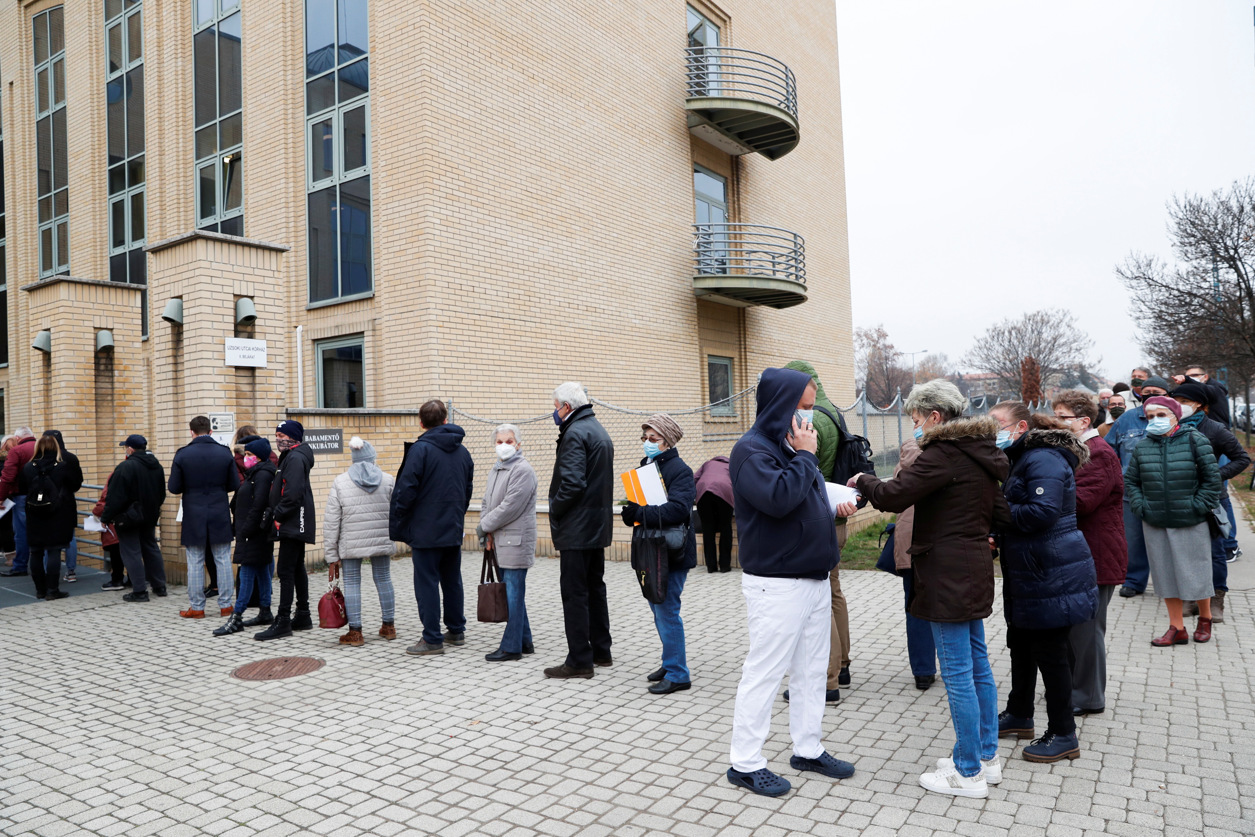 People stand in a queue for vaccination in front of a hospital as the spread of the coronavirus disease (COVID-19) continues, in Budapest, Hungary, November 22, 2021. REUTERS/Bernadett Szabo