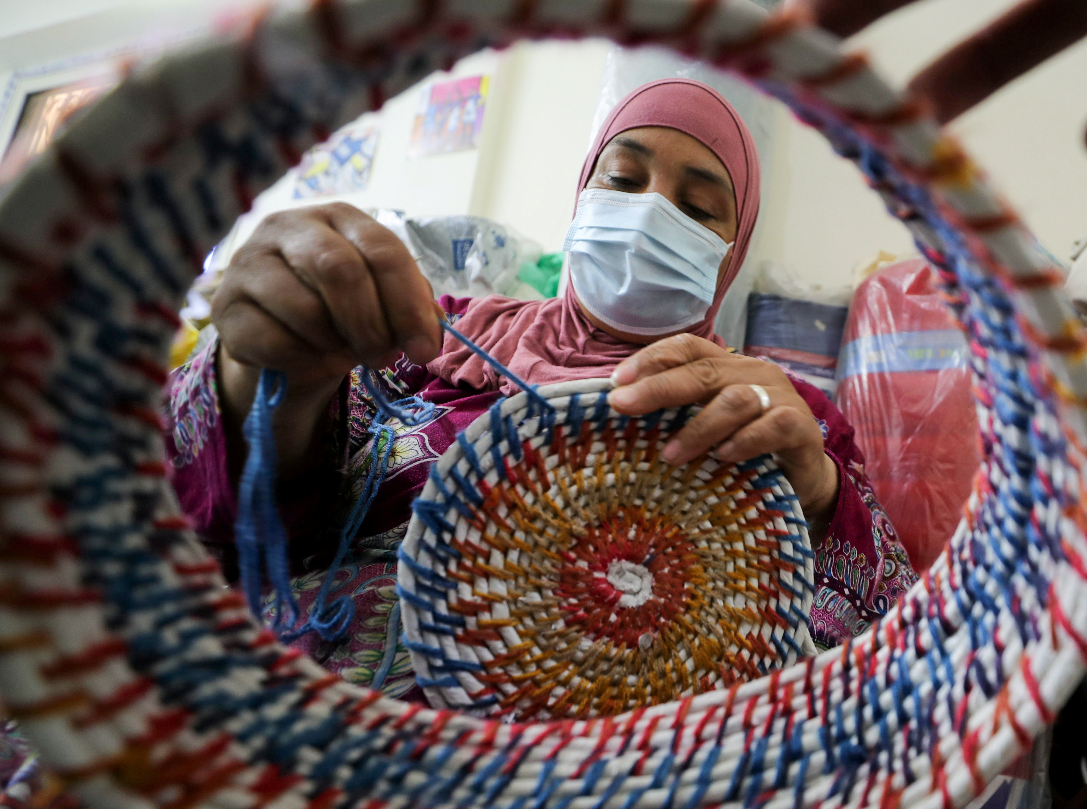 Woman knits a craft from the recycled plastic garbage that was collected from the Nile river in Giza