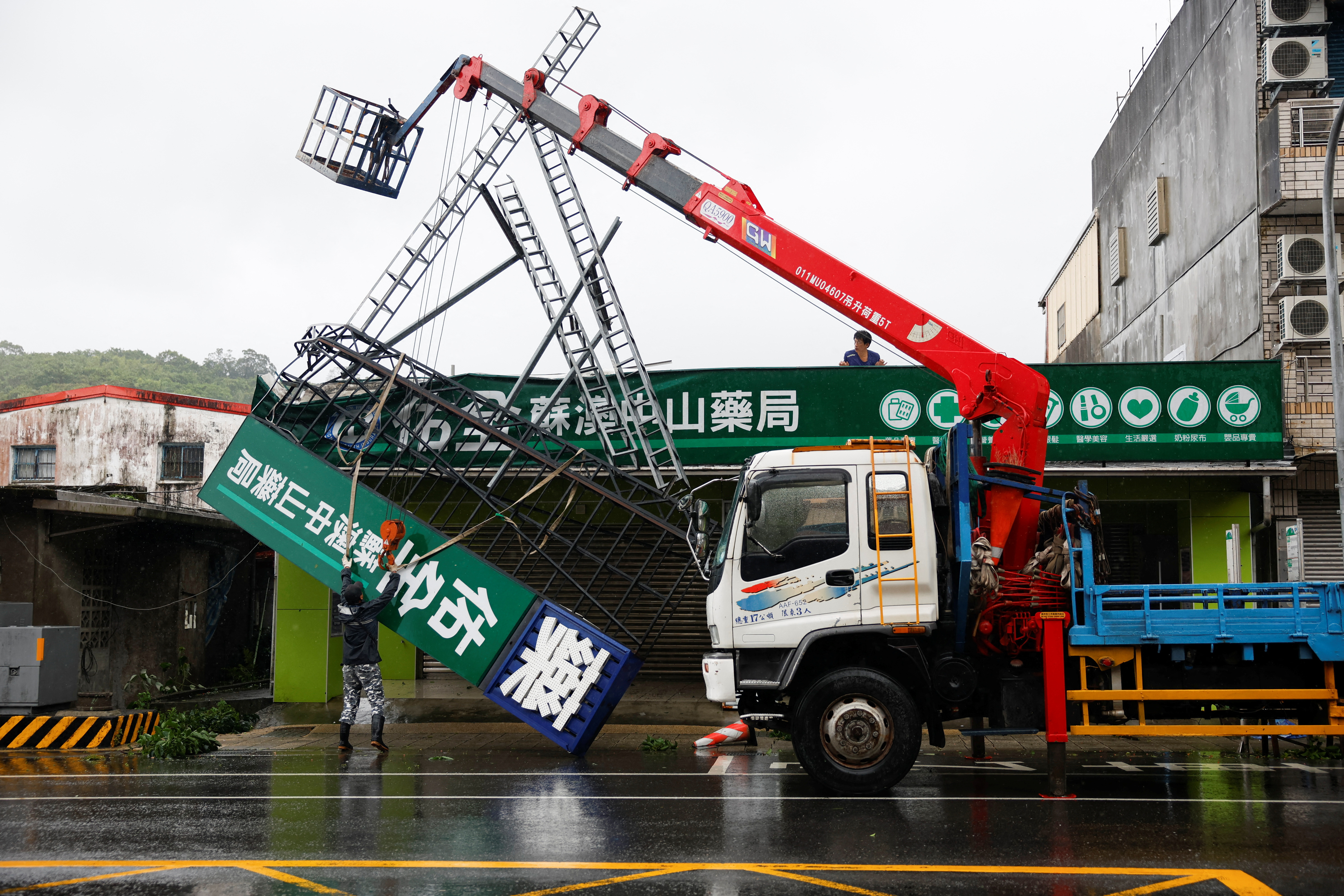 Workers use a crane to remove a fallen sign after Typhoon Gaemi passed northern Taiwan in Yilan