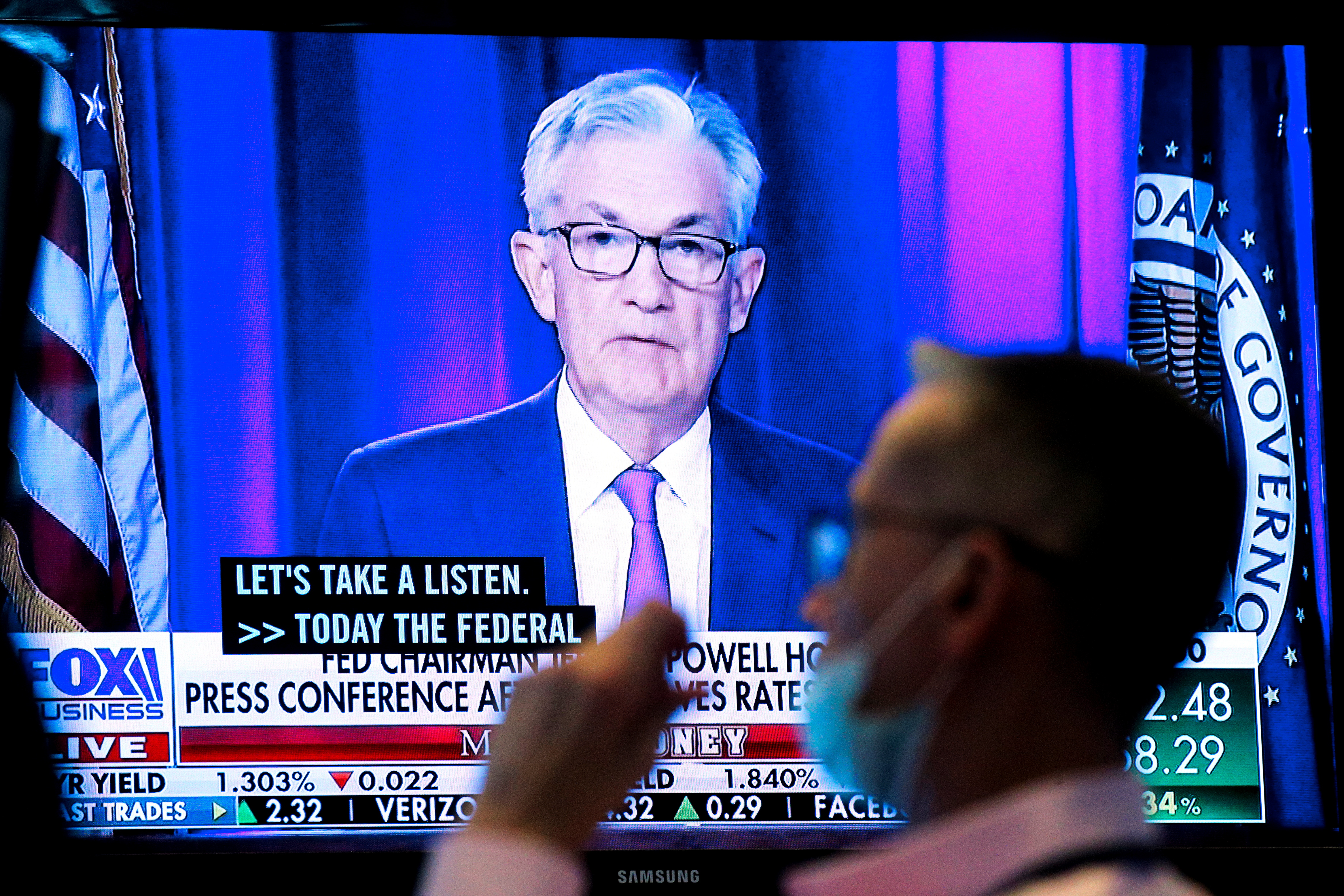 A screen displays a statement by Federal Reserve Chair Jerome Powell following the U.S. Federal Reserve's announcement as a trader works on the trading floor of the NYSE in New York