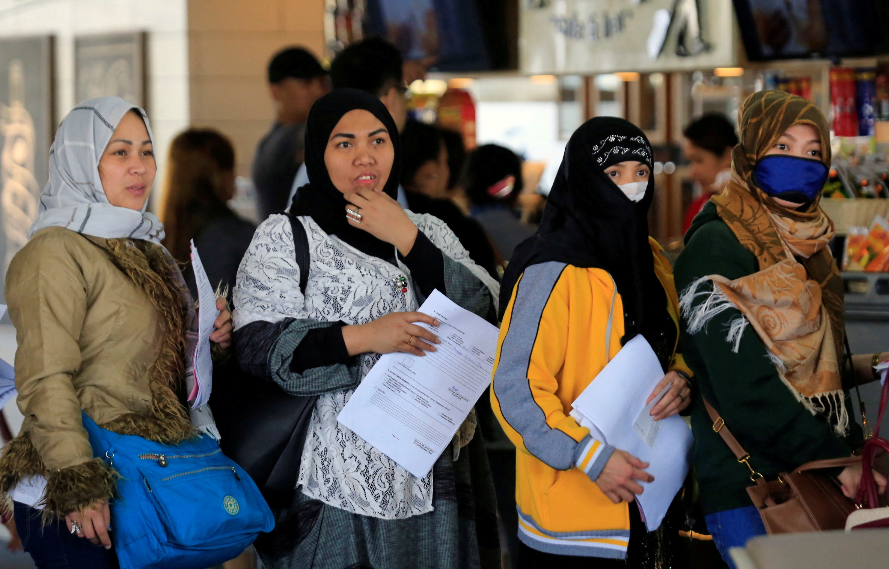 Overseas Filipino Workers (OFW) from Kuwait hold their documents as they queue upon their arrival at the Ninoy Aquino International Airport in Pasay city, Metro Manila