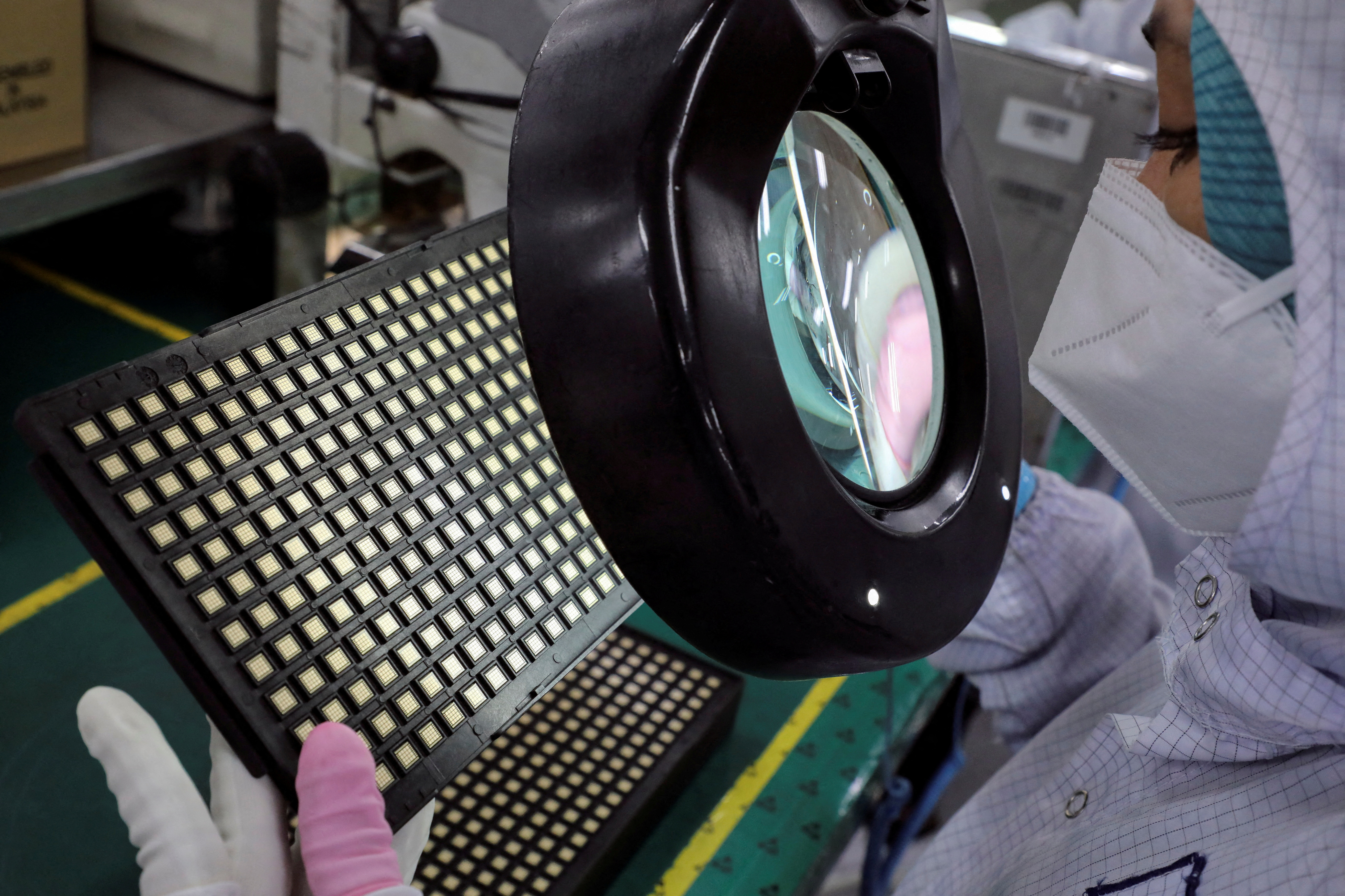 A worker inspects semiconductor chips at the chip packaging firm Unisem (M) Berhad plant in Ipoh