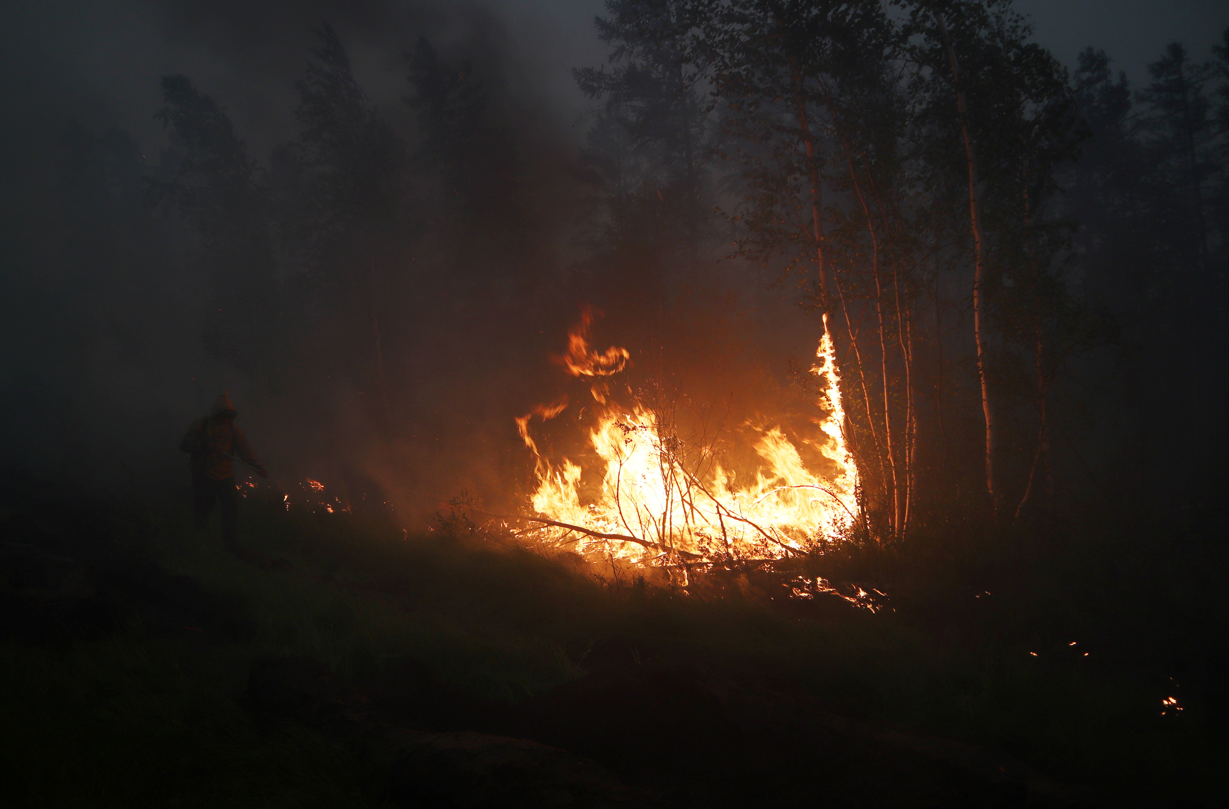 A firefighter works to extinguish a forest fire in Yakutia