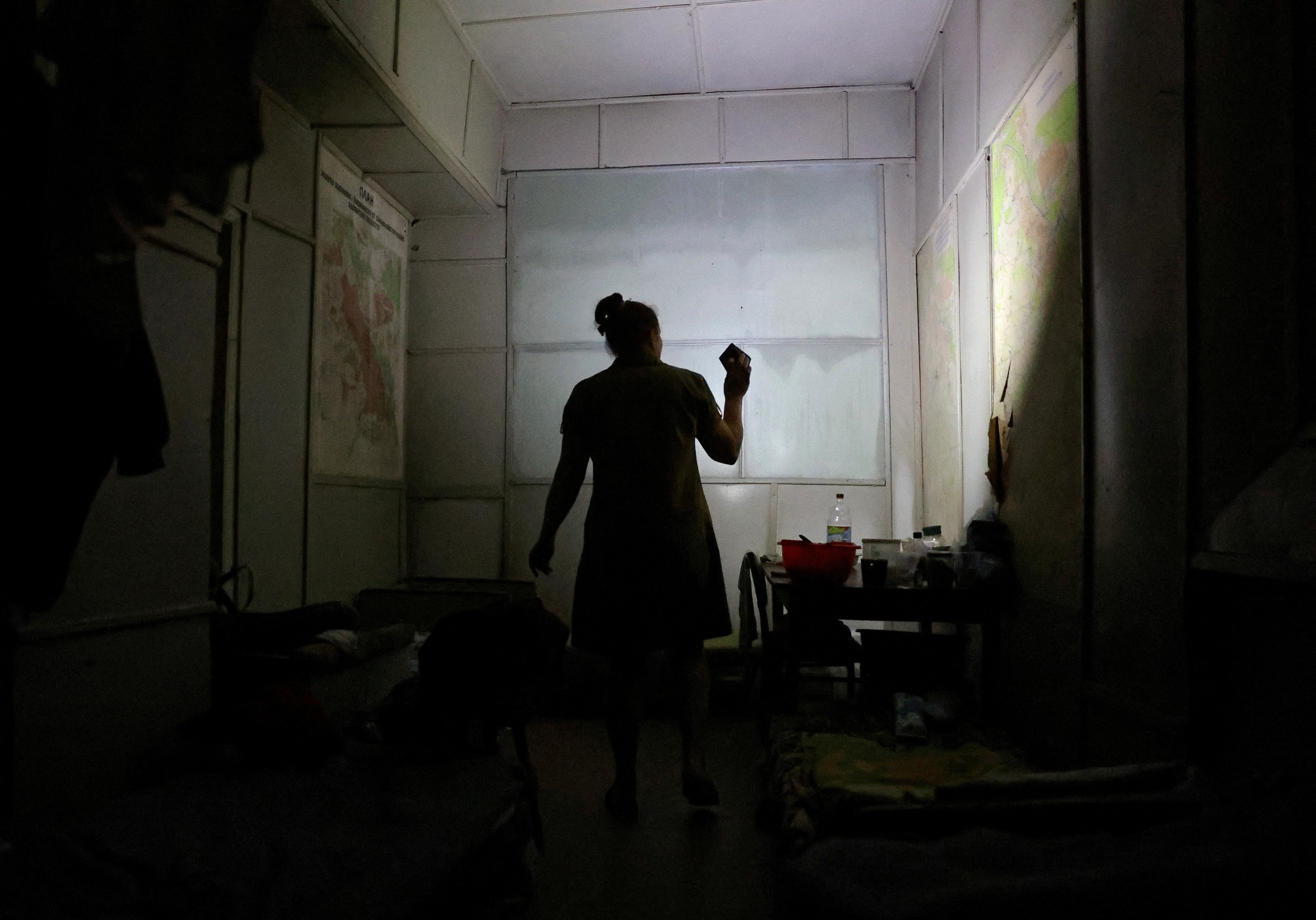 Local resident Tatiana Glushenko uses a flashlight inside a glass factory bomb shelter in Lysychansk