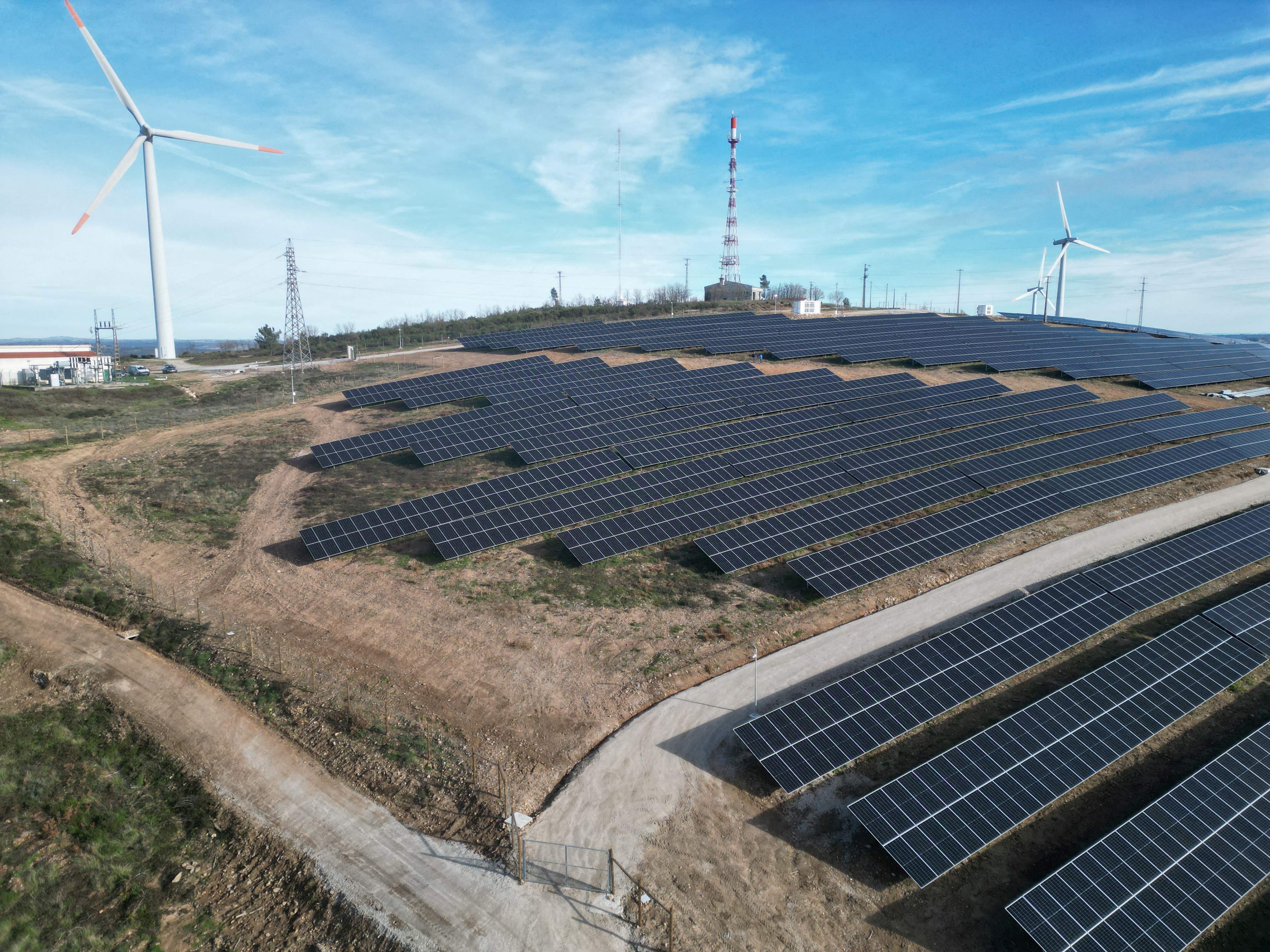 Drone view of a hybrid power park with solar panels and wind turbines in Sabuga, Portugall