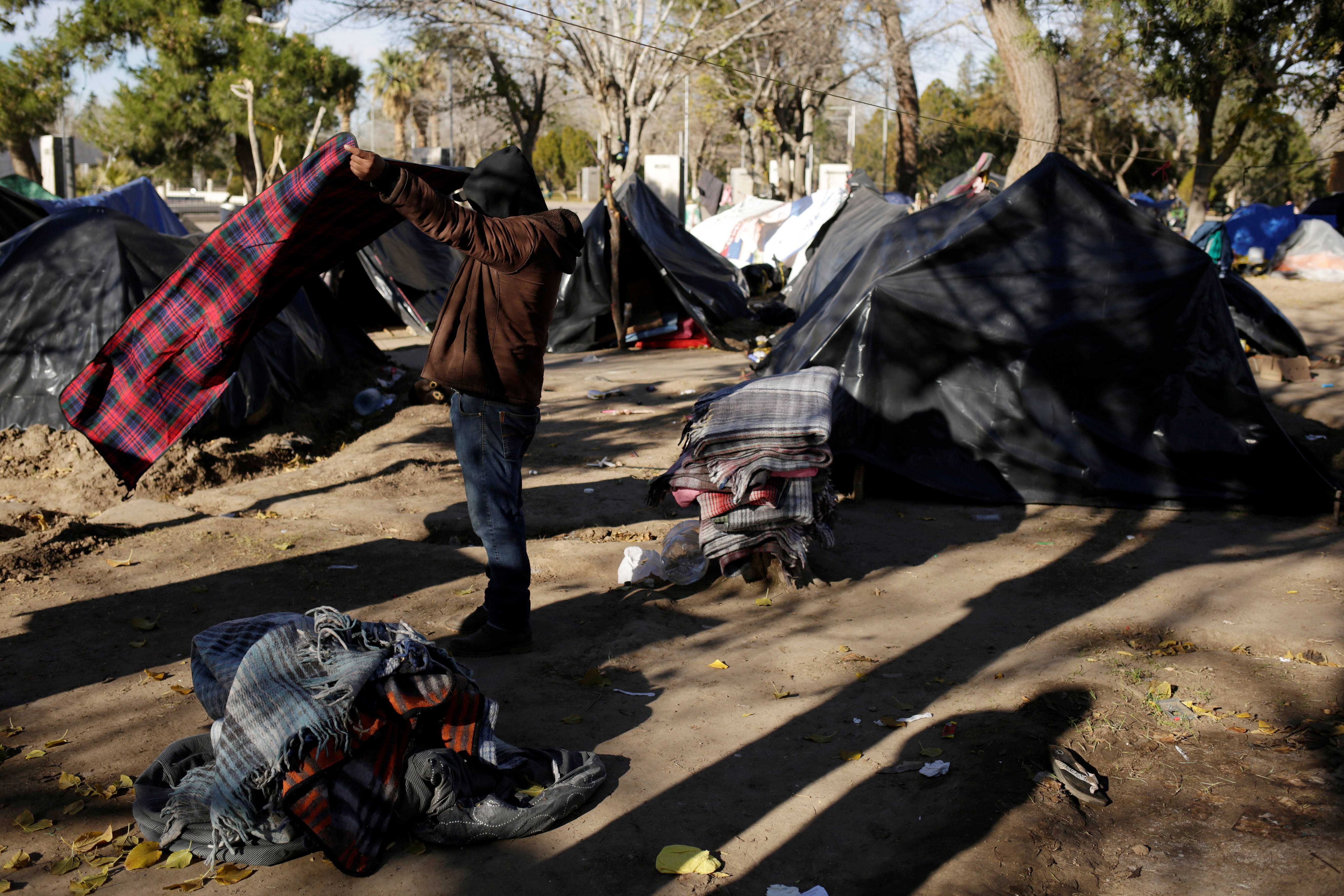 A Mexican man, who is fleeing from violence in his hometown and is currently camping near the Cordova-Americas international border crossing bridge while waiting to apply for asylum to the U.S., packs his belongings to move to a shelter as temperatures dropped below freezing in Ciudad Juarez, Mexico, December 18, 2019. REUTERS/Jose Luis Gonzalez