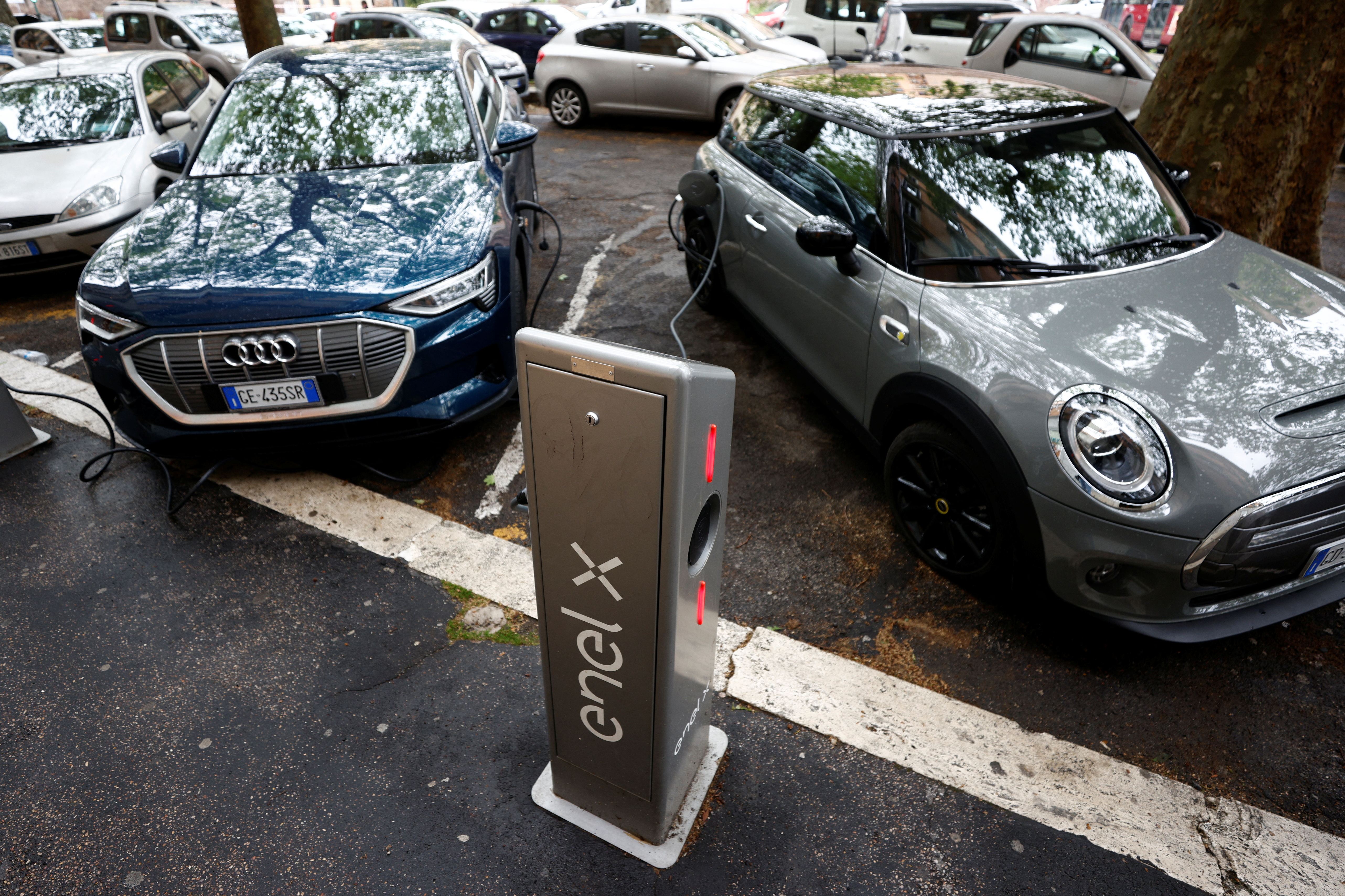 Electric cars are plugged in at a charging point for electric vehicles in Rome