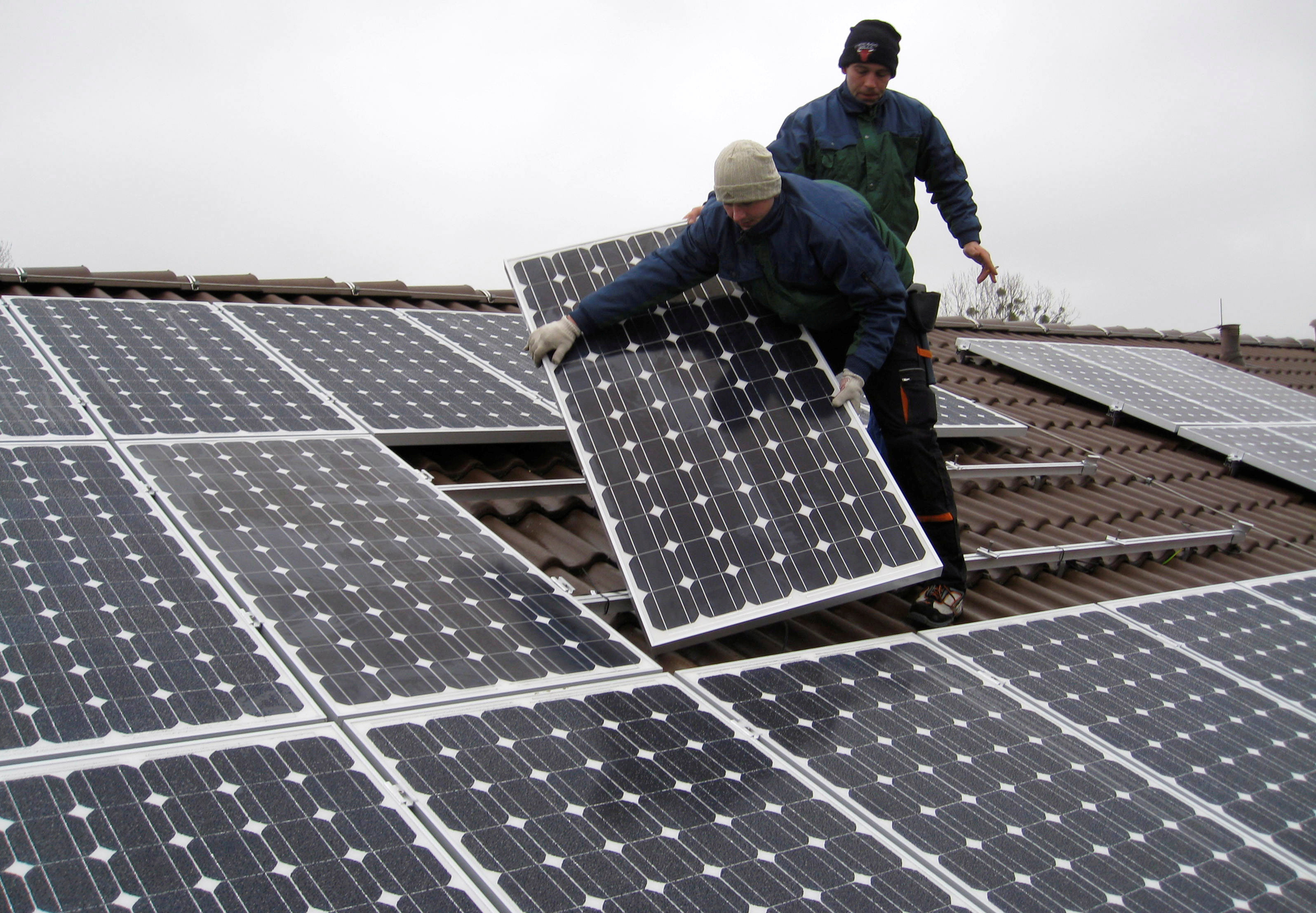 Workers install solar panels on a roof near Berlin