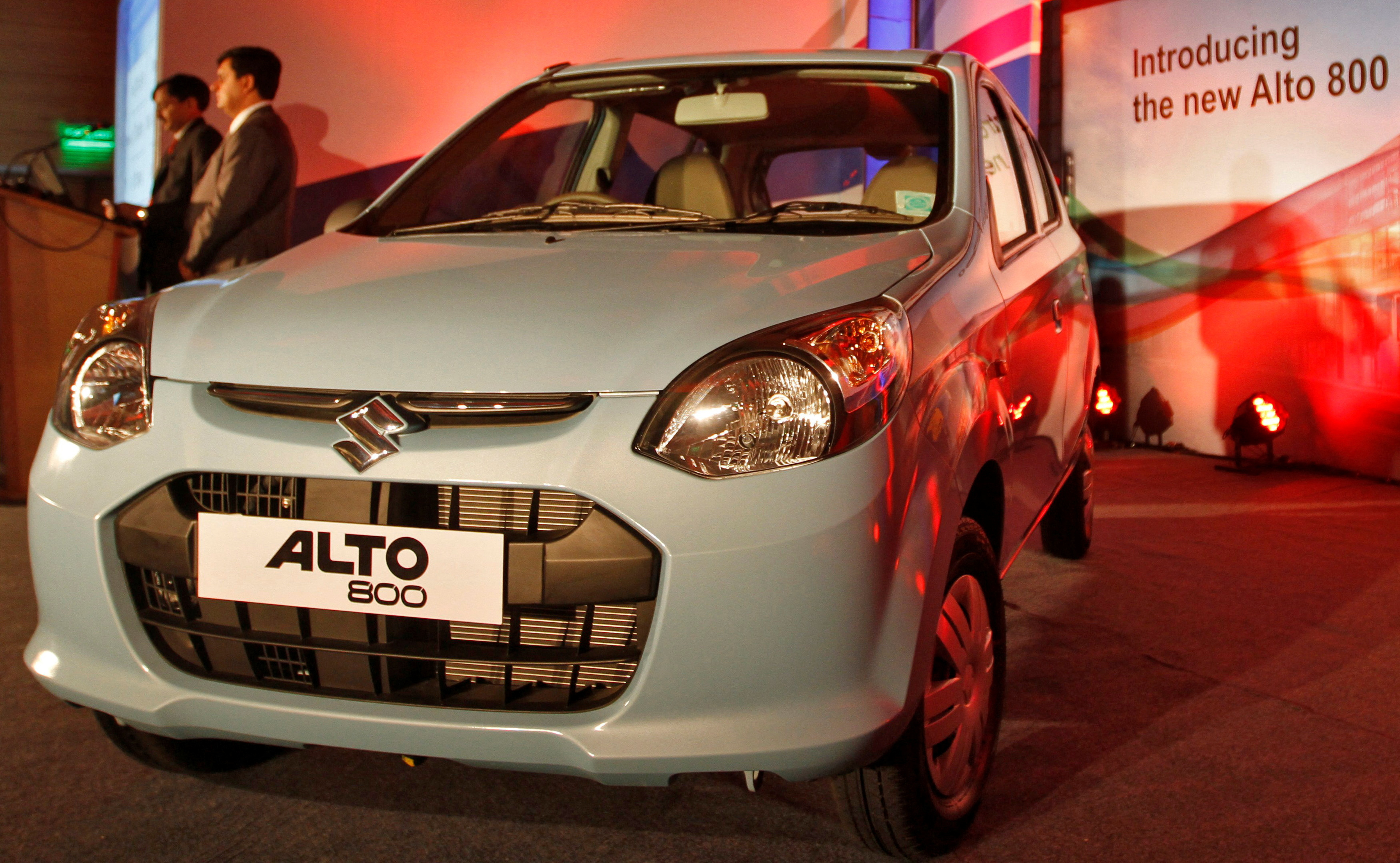 Officials stand next to the newly launched Maruti Suzuki Alto 800 car in Ahmedabad
