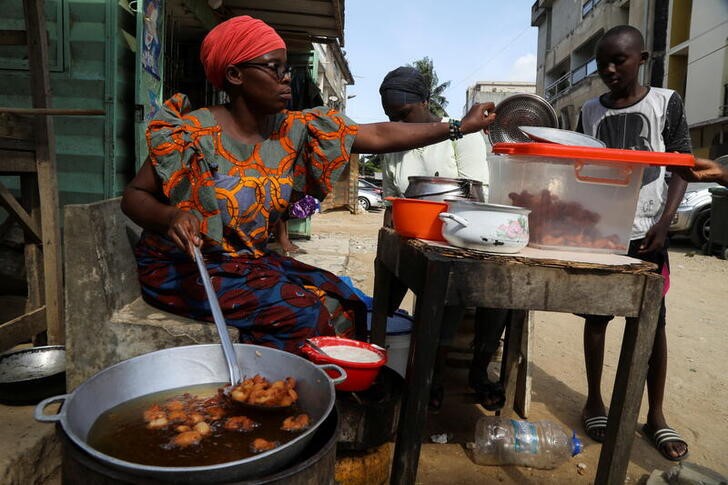 Djeneba Belem prepares to sell bean cakes which she fries in cooking oil made from palm oil, on a street in Abidjan