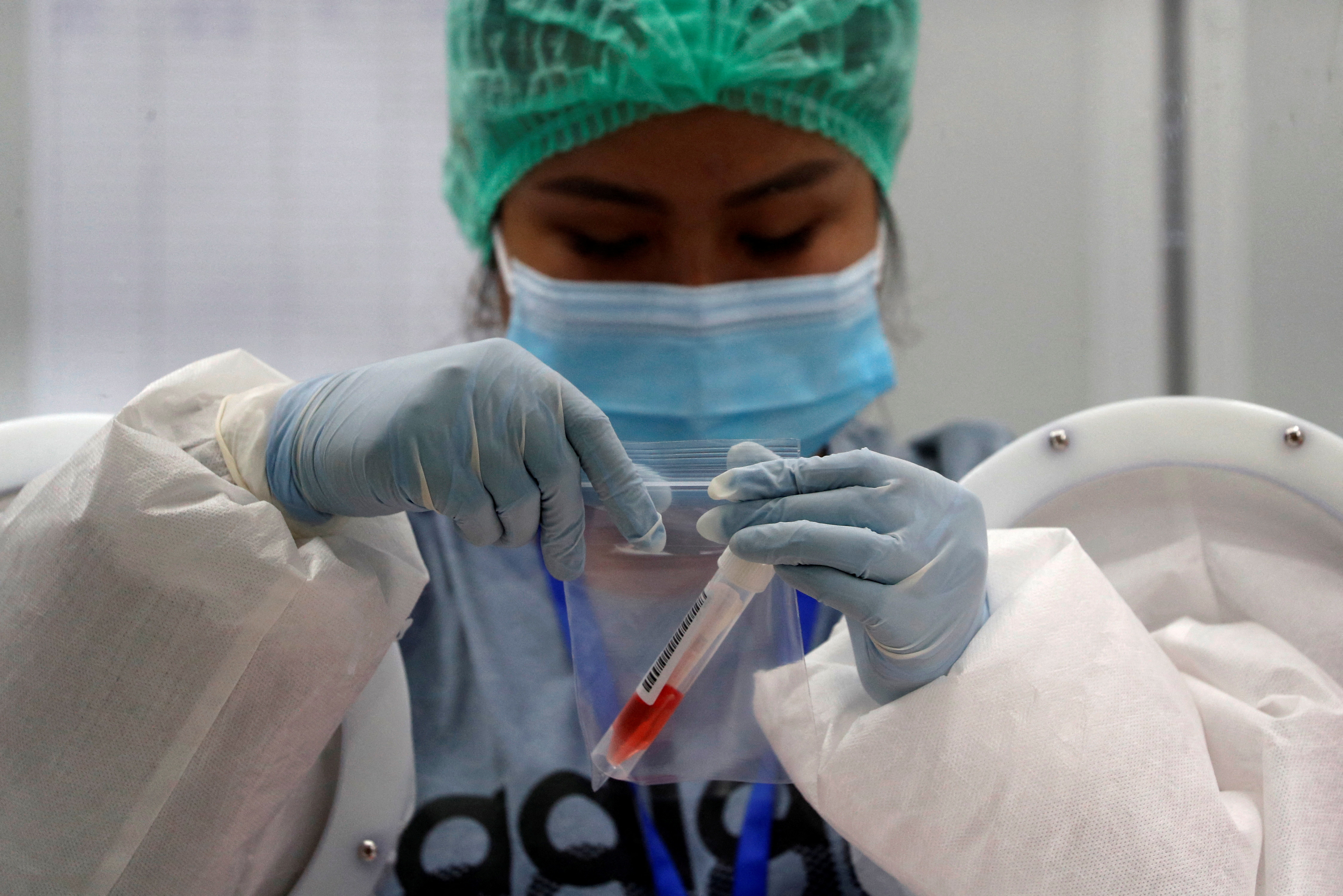 A nurse closes a bag that contains a sample collected from a passenger as it's mandatory to check all arriving passengers to prevent the spread of the coronavirus disease, at the international airport in Phuket