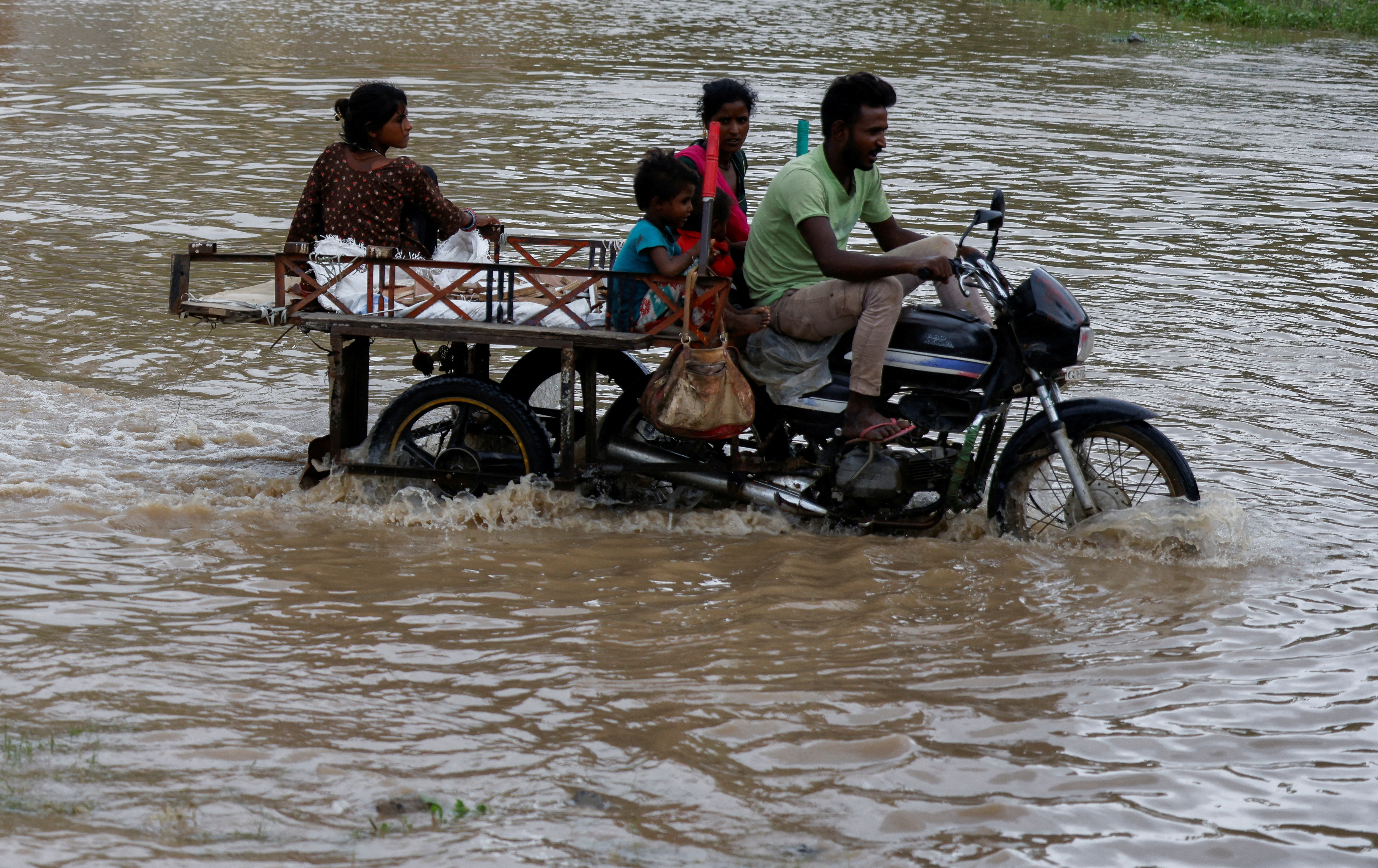 A family crosses a flooded street after heavy rains in Ahmedabad