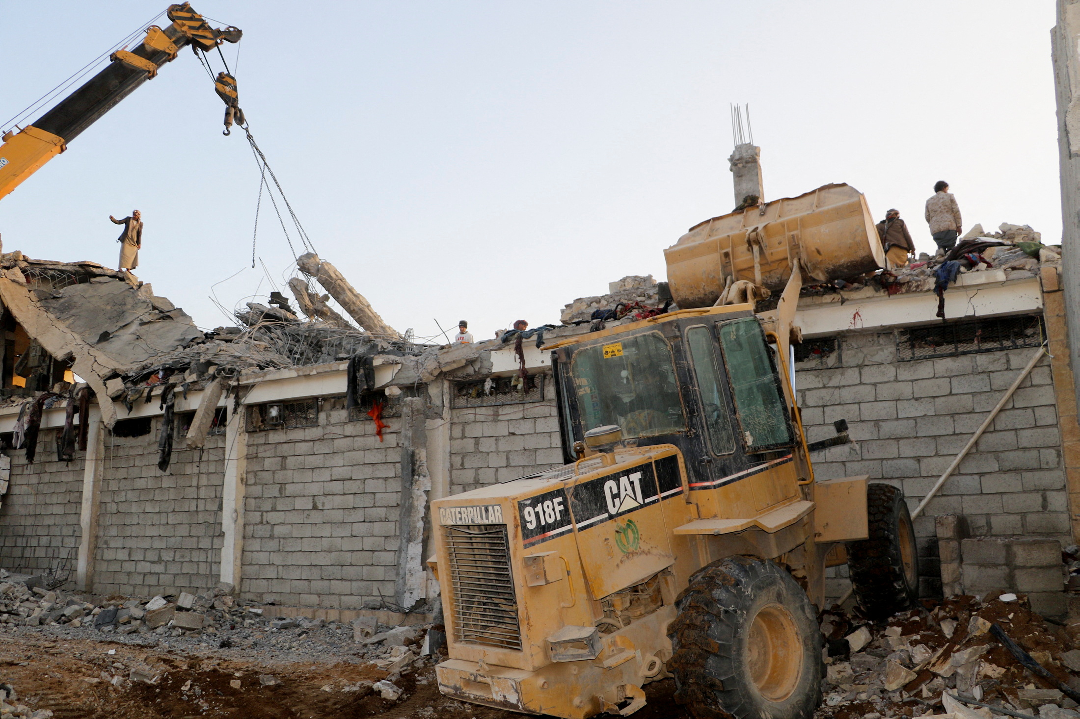 Rescuers use a bulldozer and a crane as they search for survivors at detention center hit by air strikes, in Saada