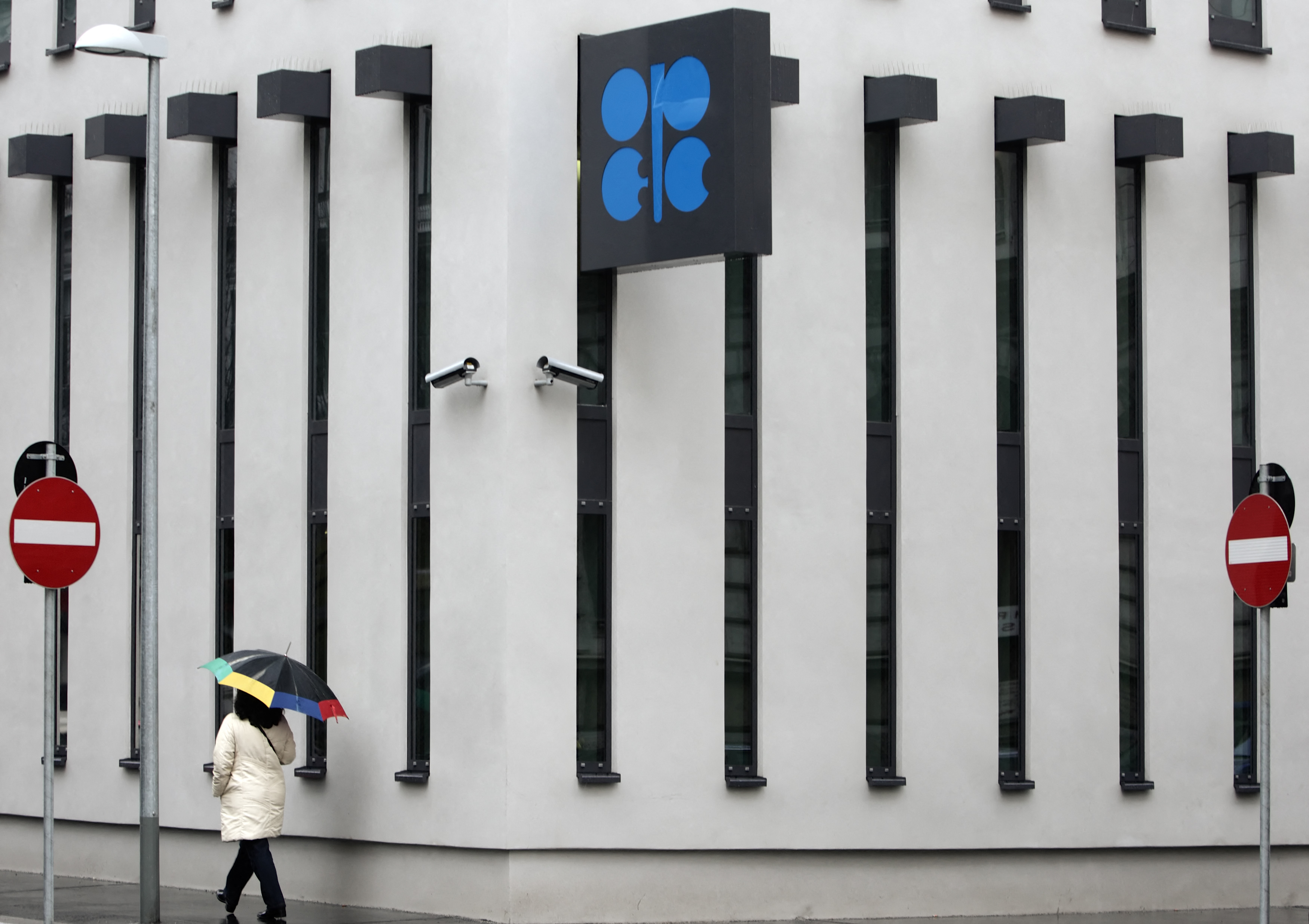 A woman with an umbrella walks past OPEC headquarters during rainfall in Vienna