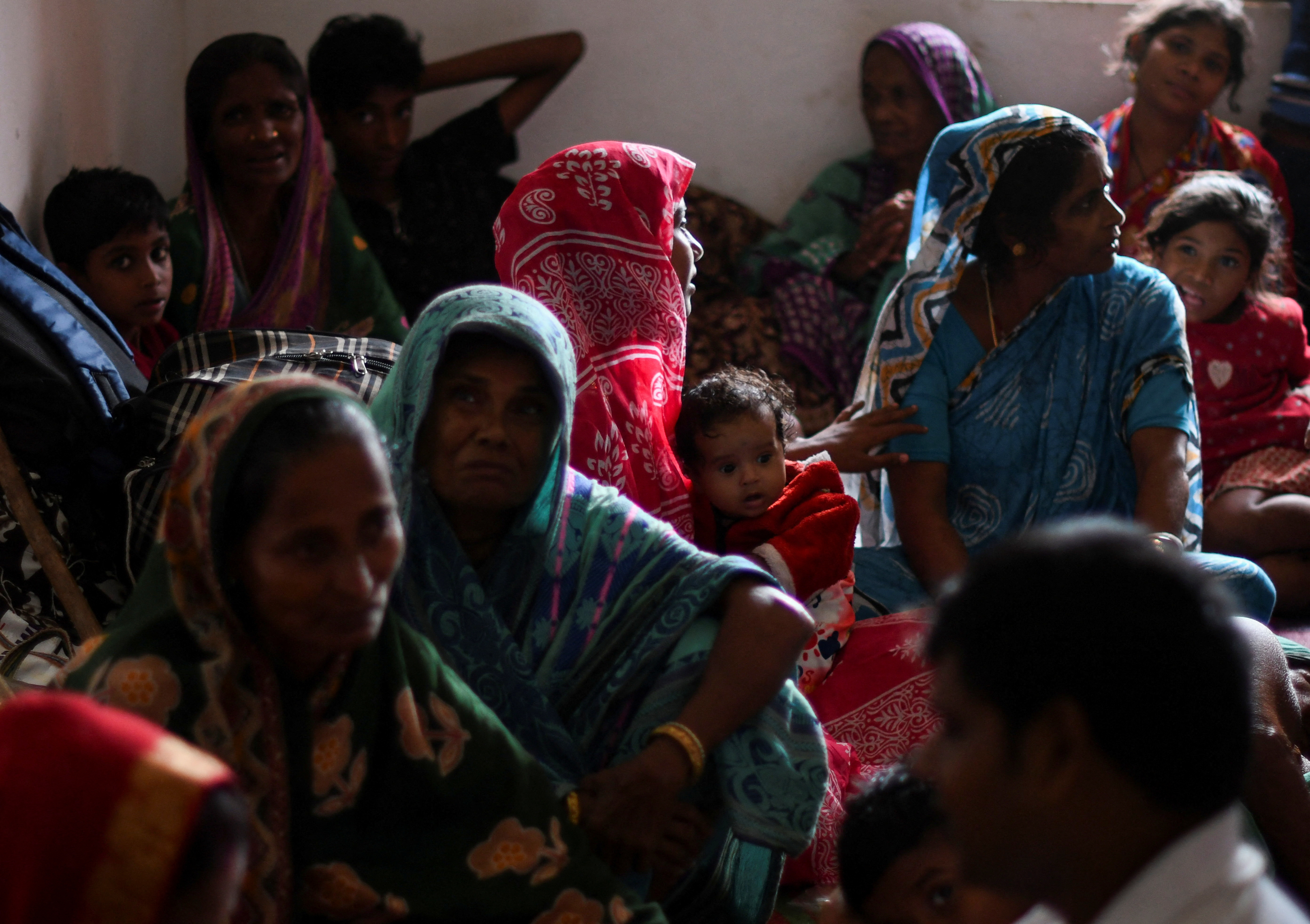 People evacuated from Amarnagar village sit inside a cyclone shelter near Dhamara fishing harbour before Cyclone Dana makes landfall, in Odisha