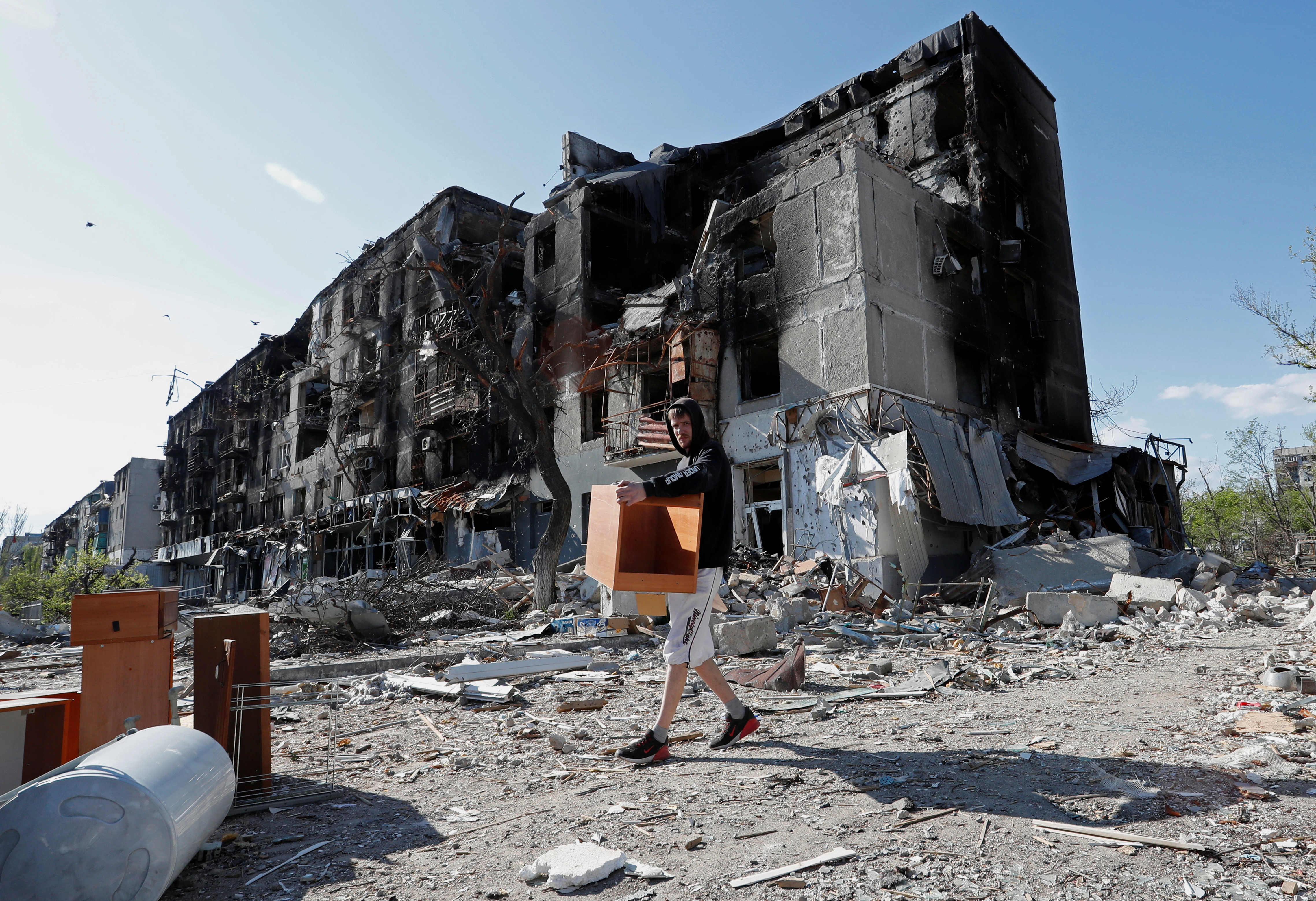 A local resident takes furniture out of a damaged apartment building in Mariupol