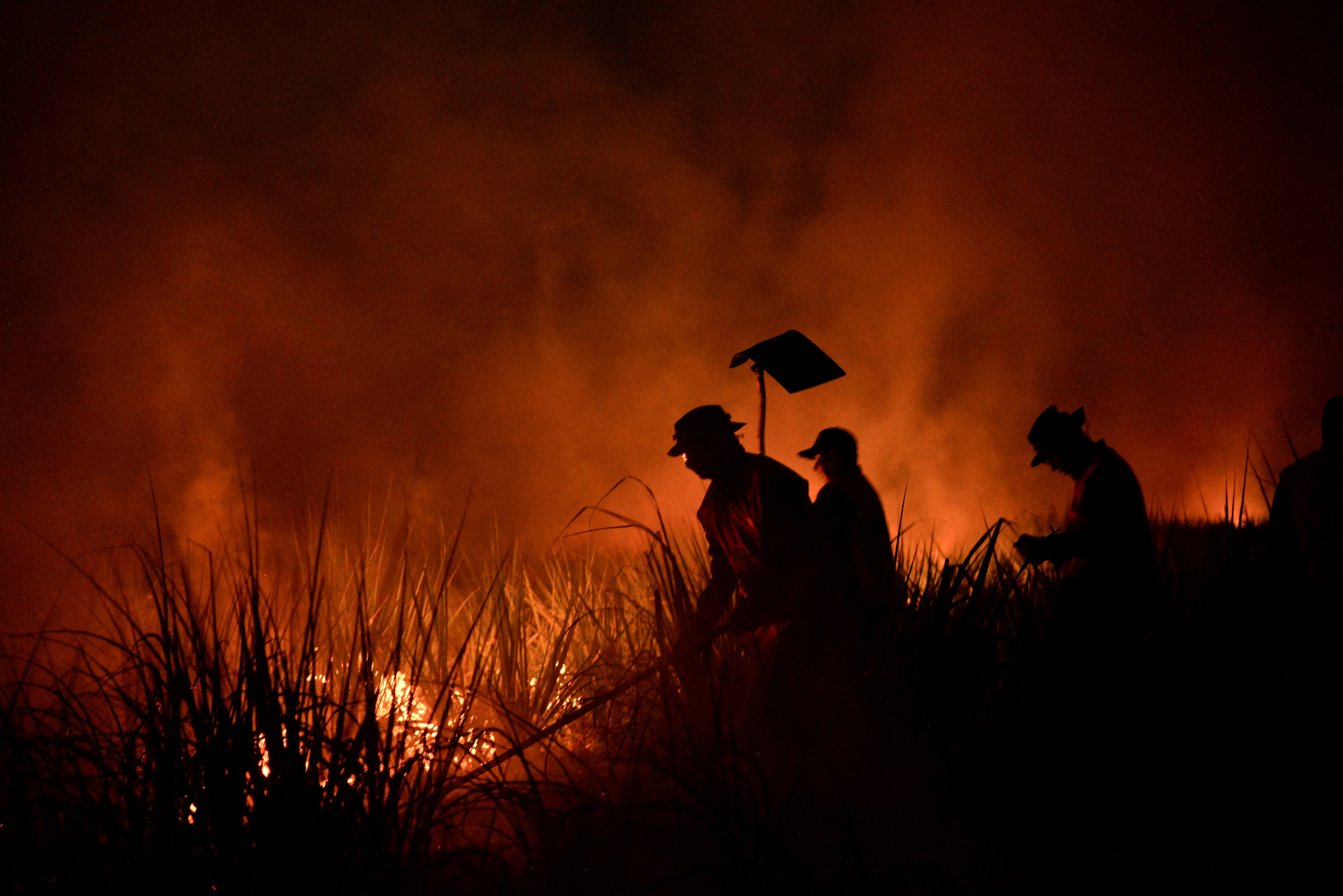 Firefighters tackle fire in a field as forest fires ravage the Bolivian Amazon, in San Buenaventura