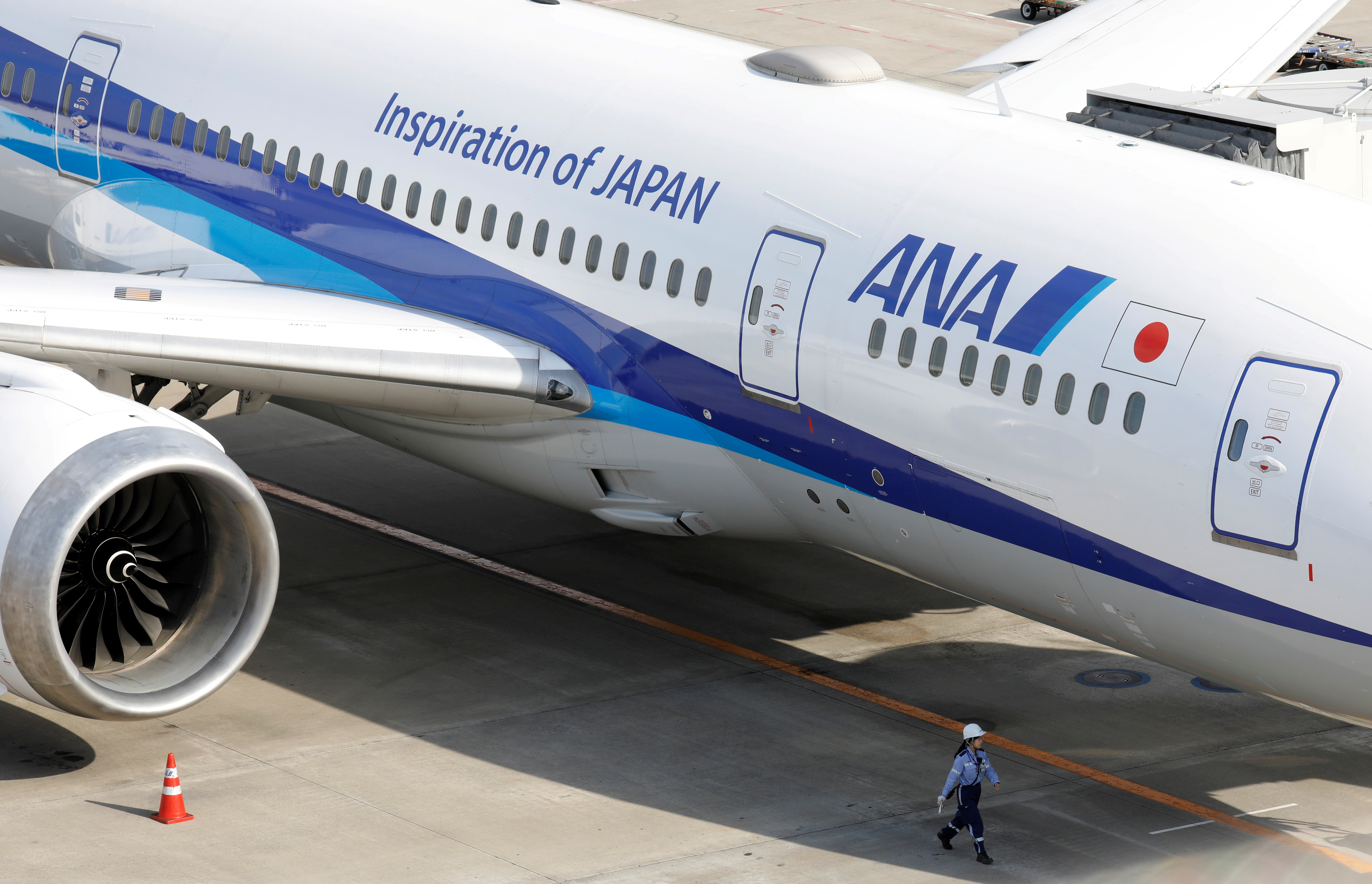 A ground crew member walks next to an All Nippon Airways (ANA) aircraft at Tokyo International Airport