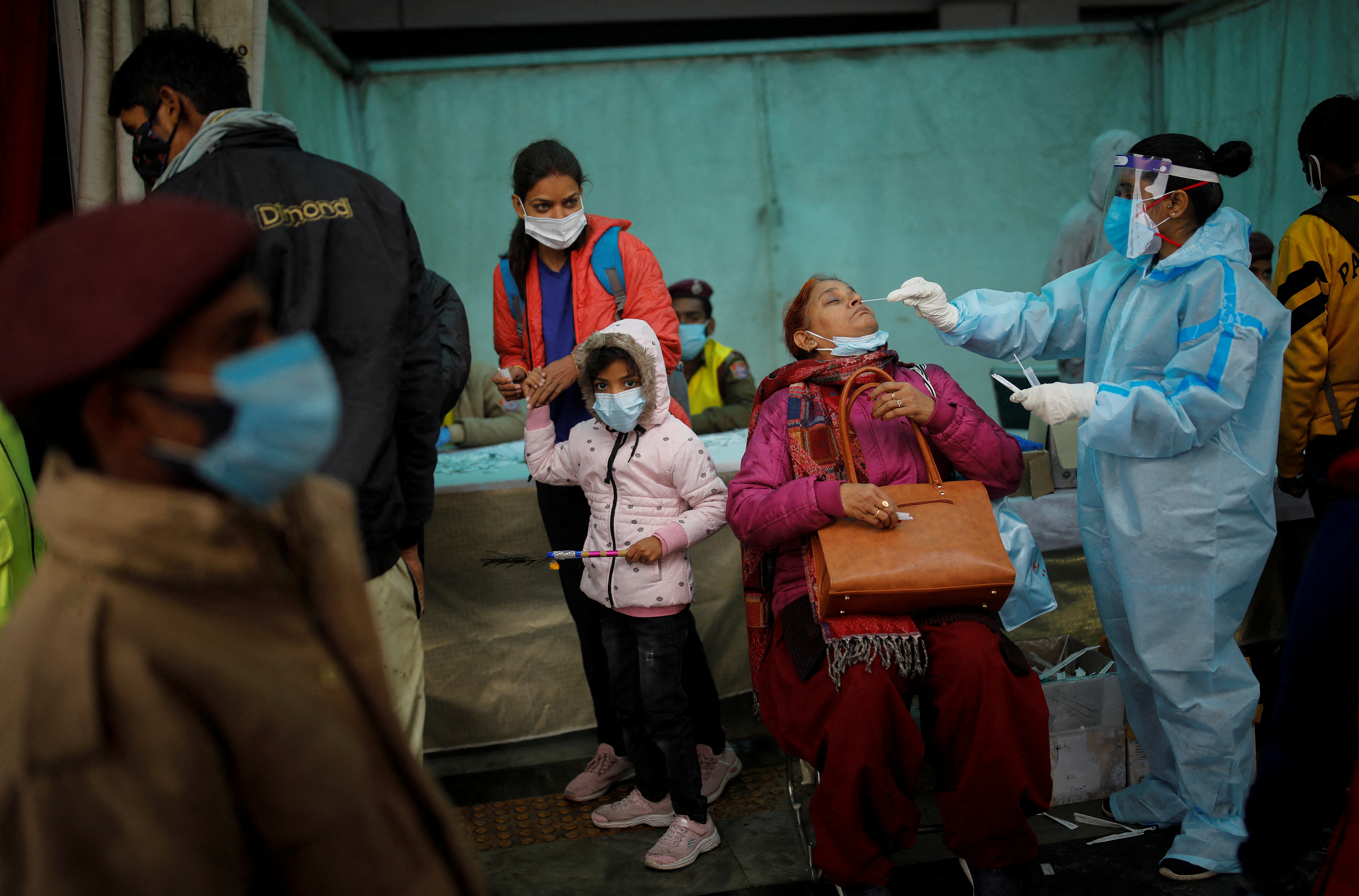 A healthcare worker collects a coronavirus disease (COVID-19) test swab sample from a woman amidst the spread of the disease, at a railway station in New Delhi, India, January 5, 2022. REUTERS/Adnan Abidi 