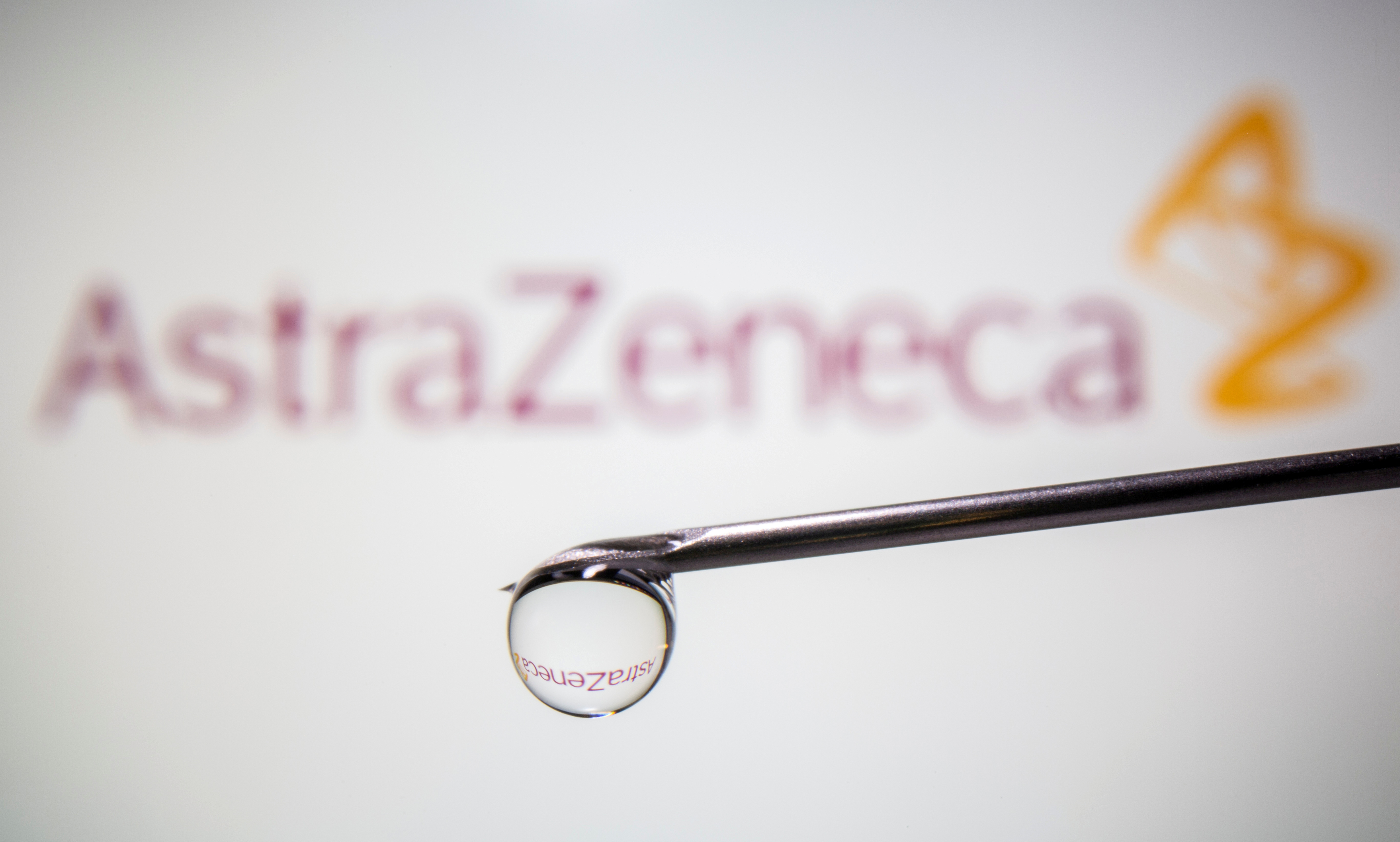 AstraZeneca's logo is reflected in a drop on a syringe needle in this illustration