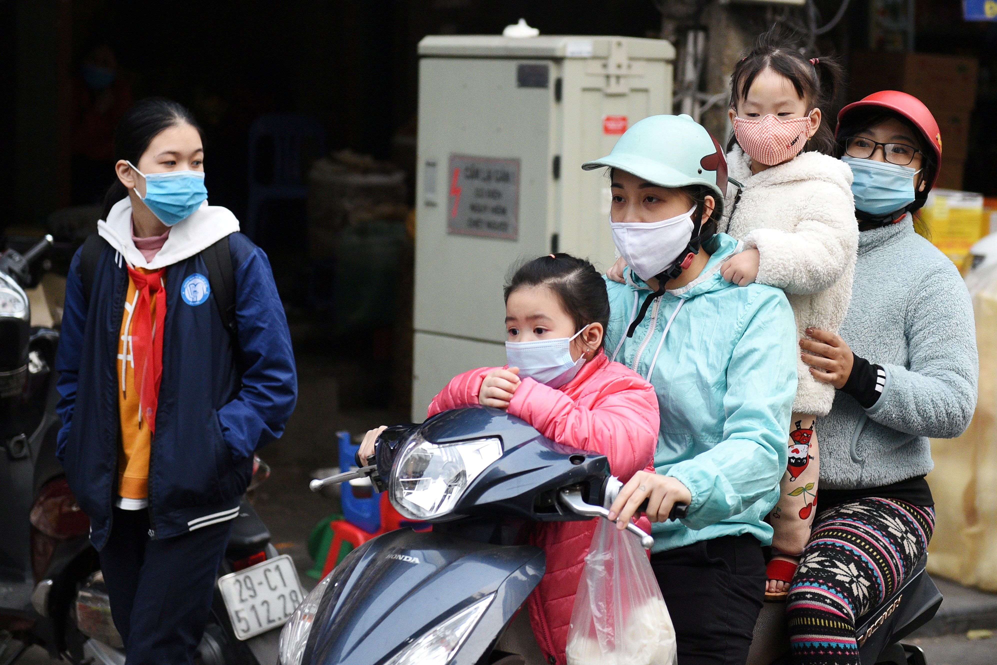 A family wears protective masks as they ride a motorbike in the street in Hanoi