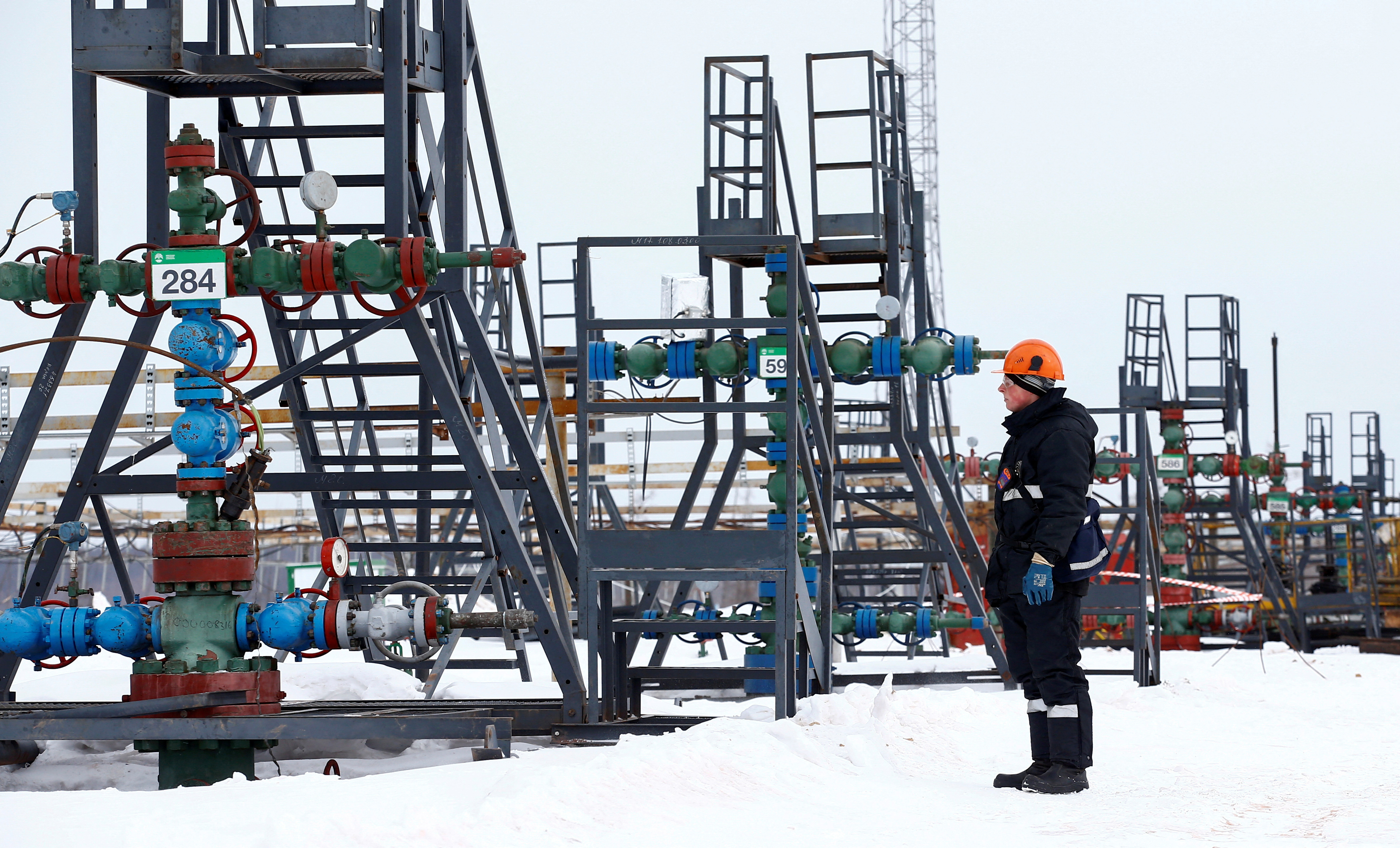 An employee inspects a well head in the Irkutsk Oil Company-owned Yarakta Oil Field in Irkutsk Region