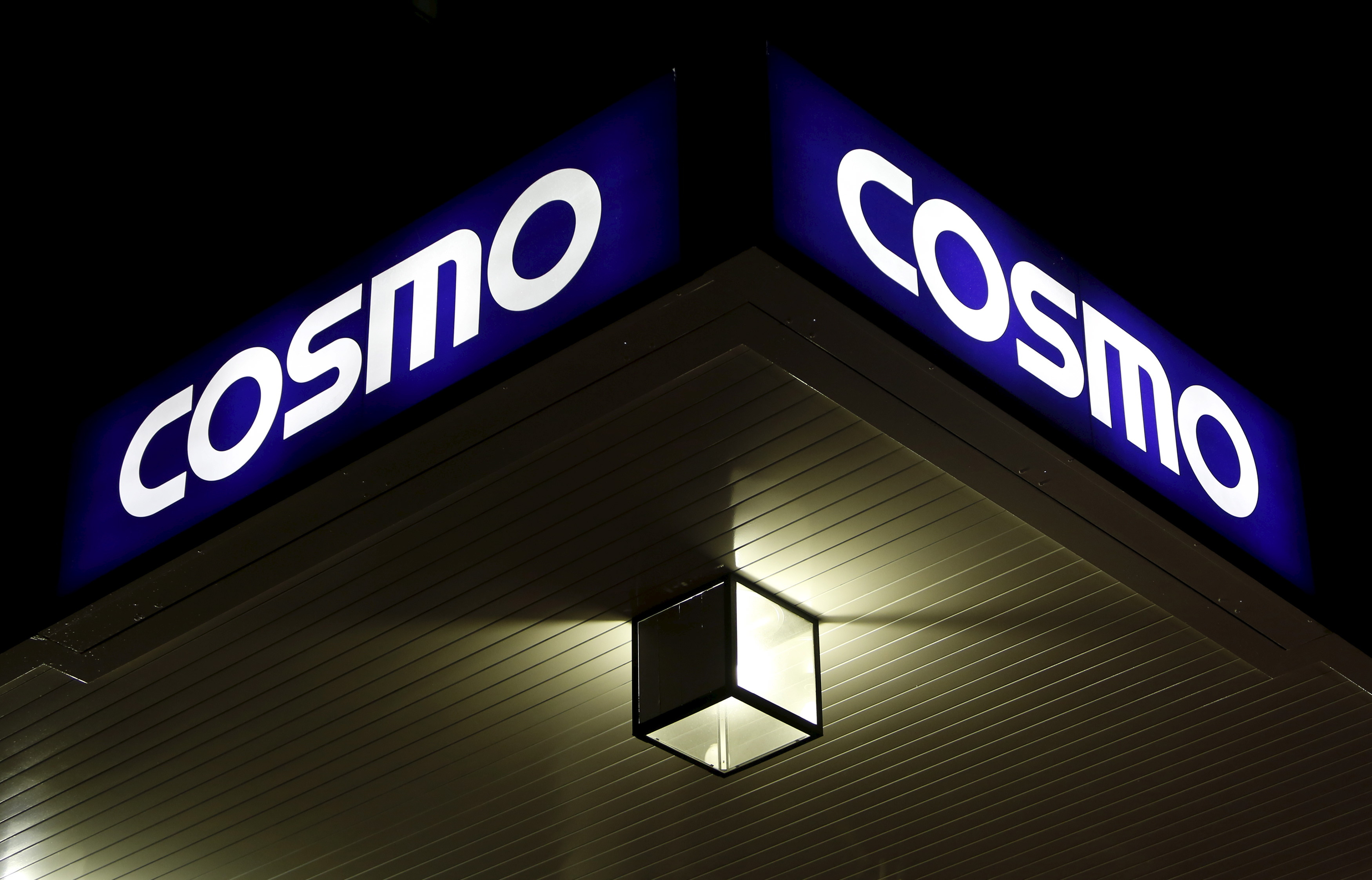 A light is seen under a signboard of Cosmo Energy Holdings' Cosmo Oil service station in Tokyo
