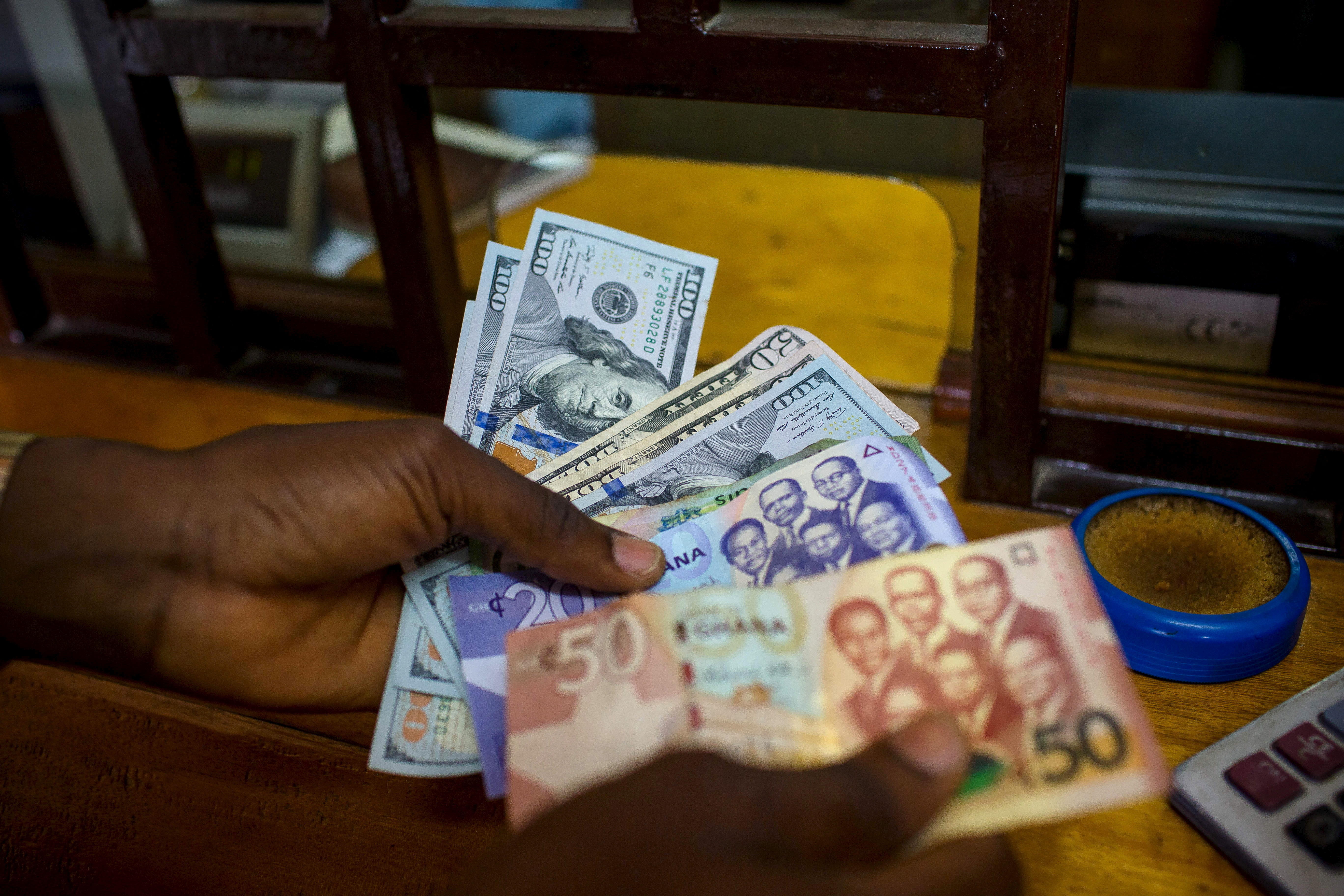 Man trades U.S. dollars for Ghanaian cedis at a currency exchange office in Accra