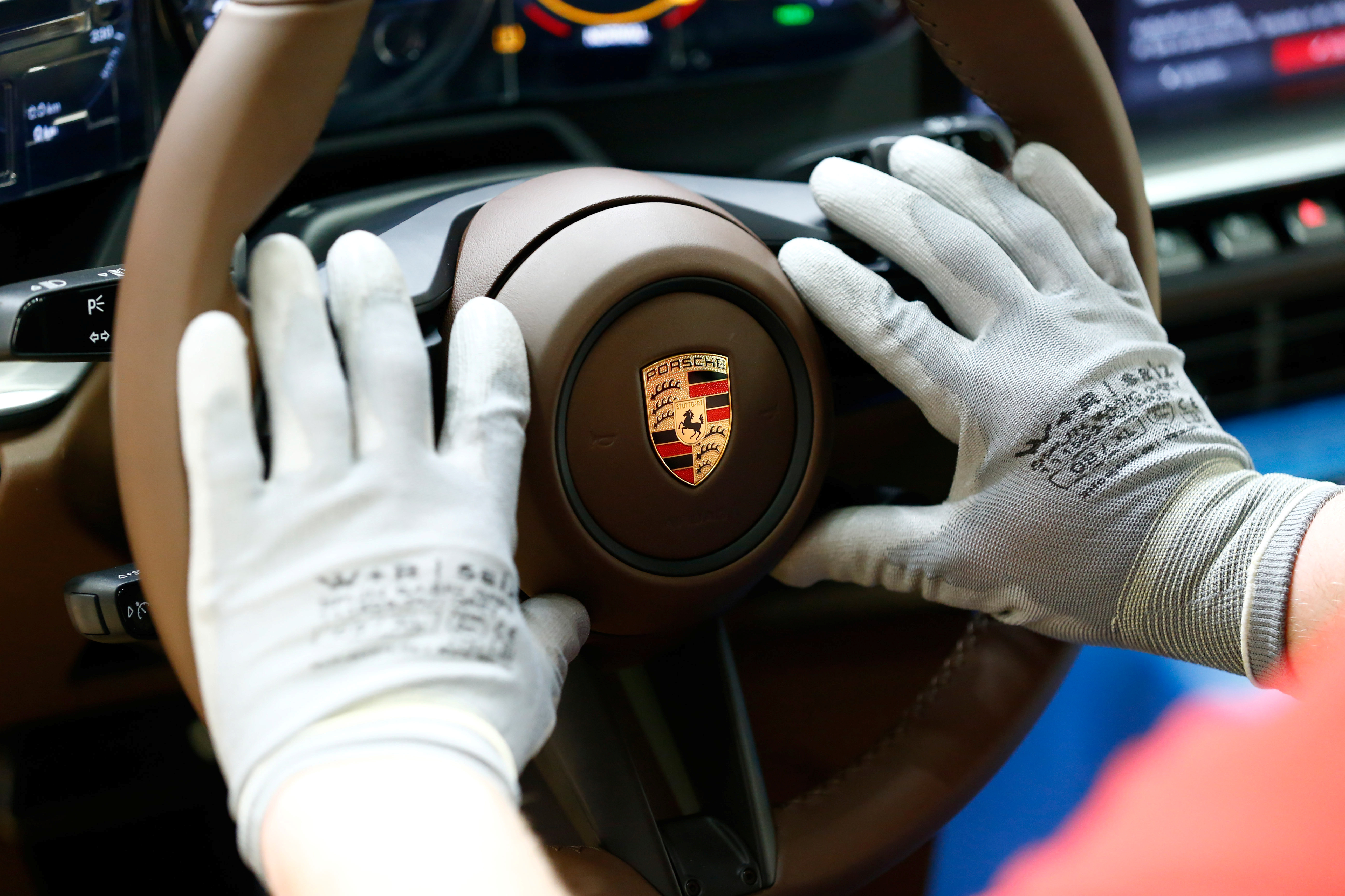 An employee of German car manufacturer Porsche mounts a steering wheel at the Porsche factory in Stuttgart-Zuffenhausen