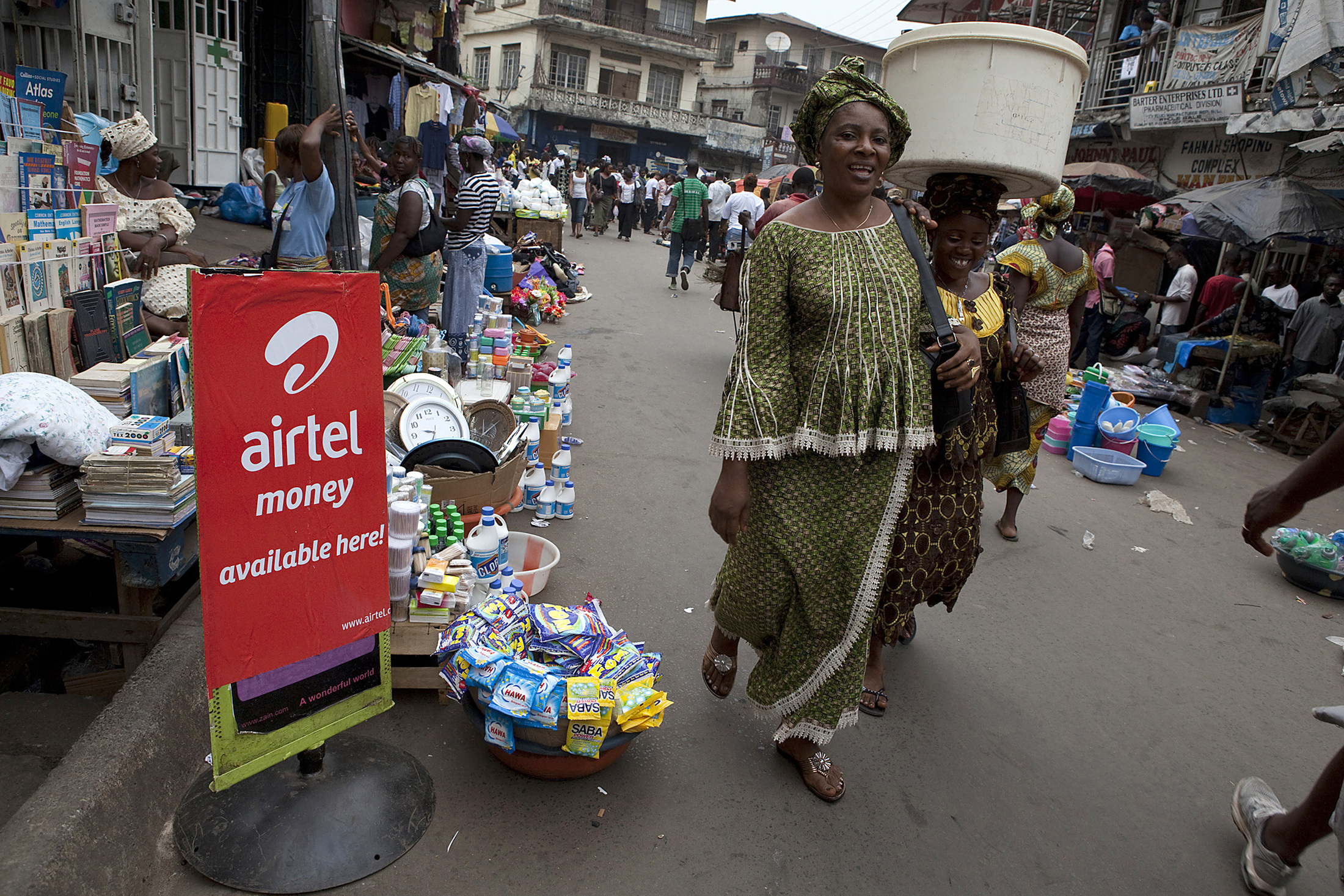 Woman walks past a sign advertising the mobile banking service Airtel Money in Freetown