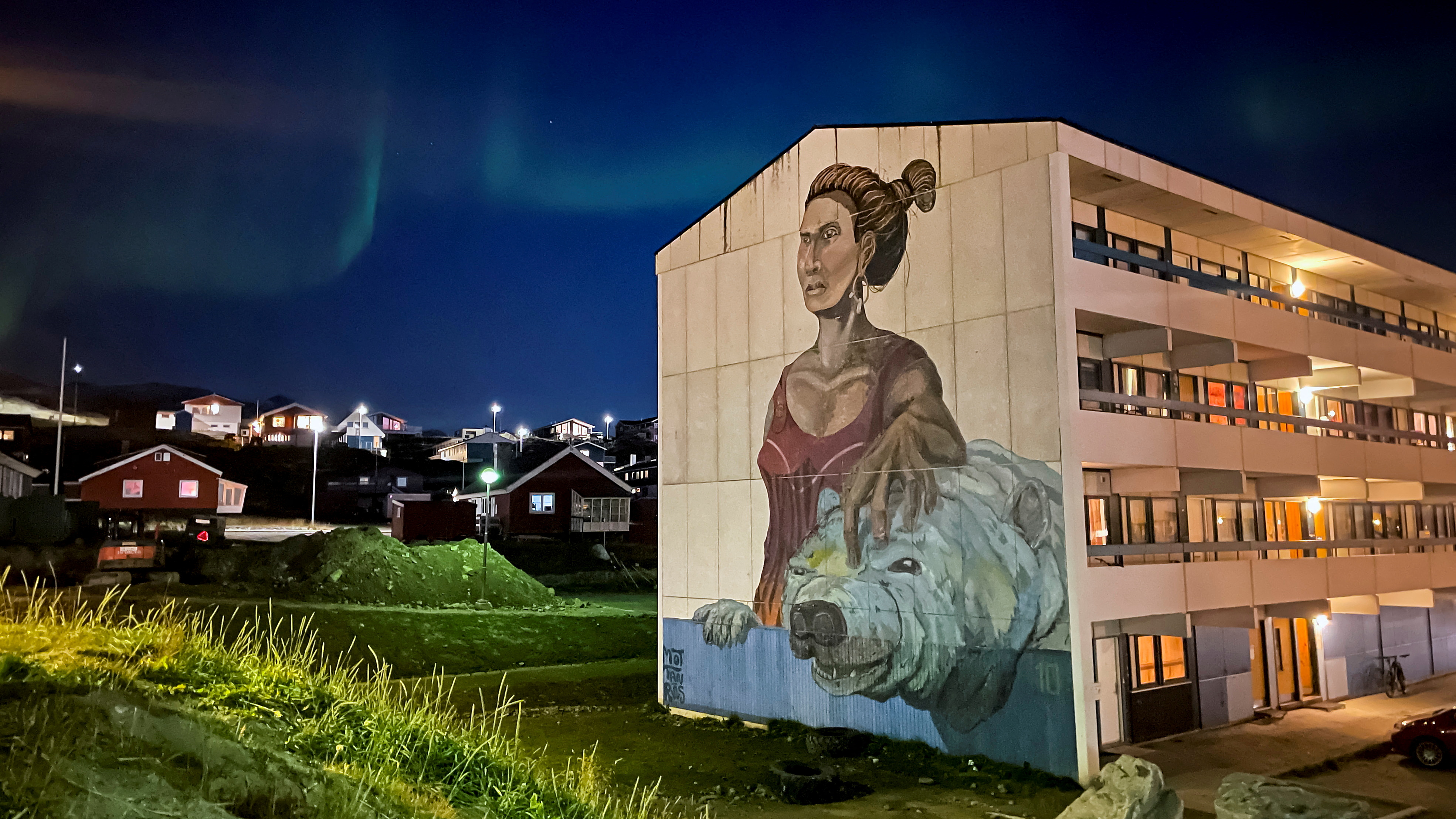 The Aurora Borealis (Northern Lights) is seen behind a building with social housings with a mural in Nuuk, Greenland, September 17, 2021.