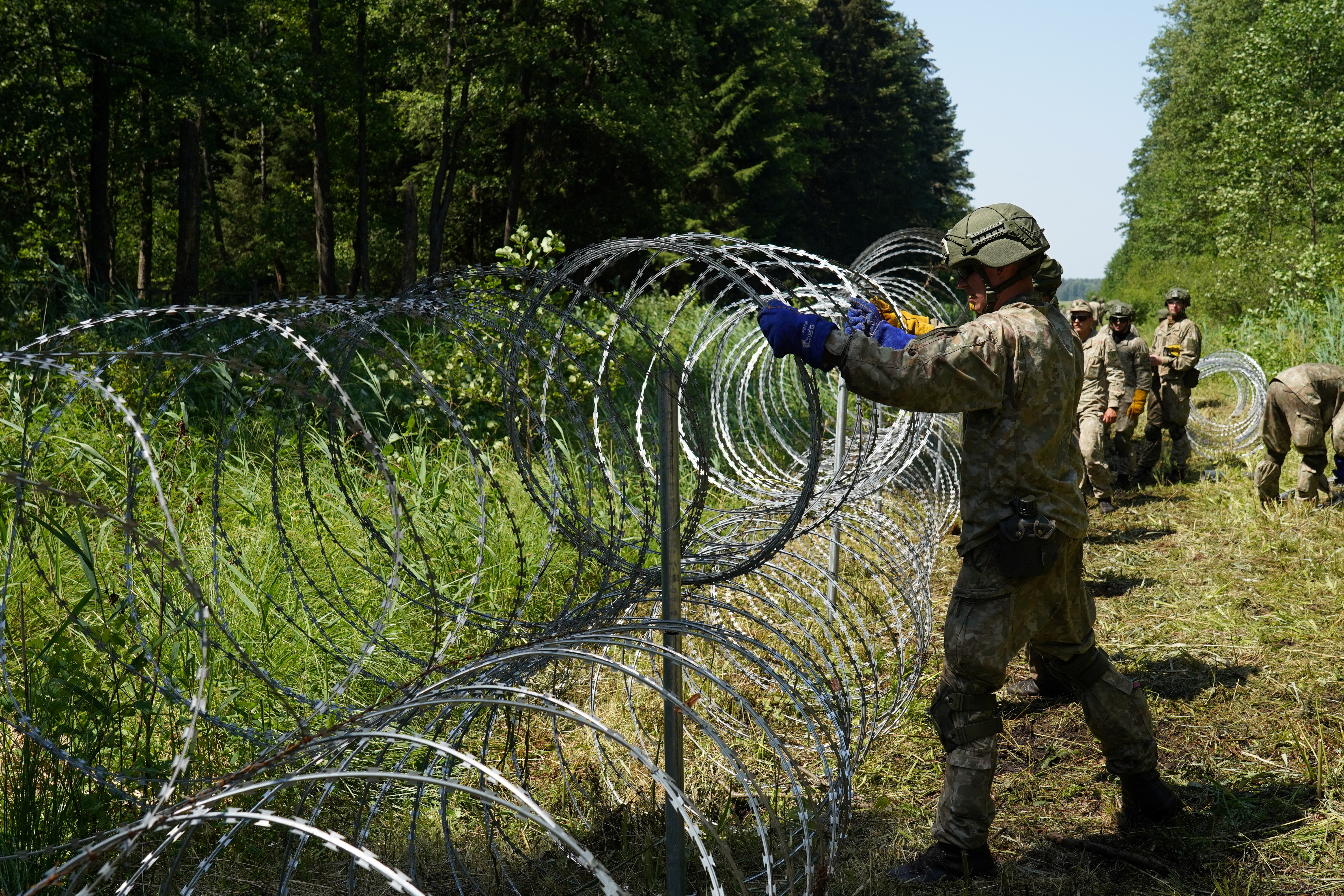 लिथुआनियाई सेना के सैनिकों ने 9 जुलाई, 2021 को ड्रुस्किनकै, लिथुआनिया में बेलारूस के साथ सीमा पर उस्तरा तार स्थापित किया। रॉयटर्स/जेनिस लाइज़न्स