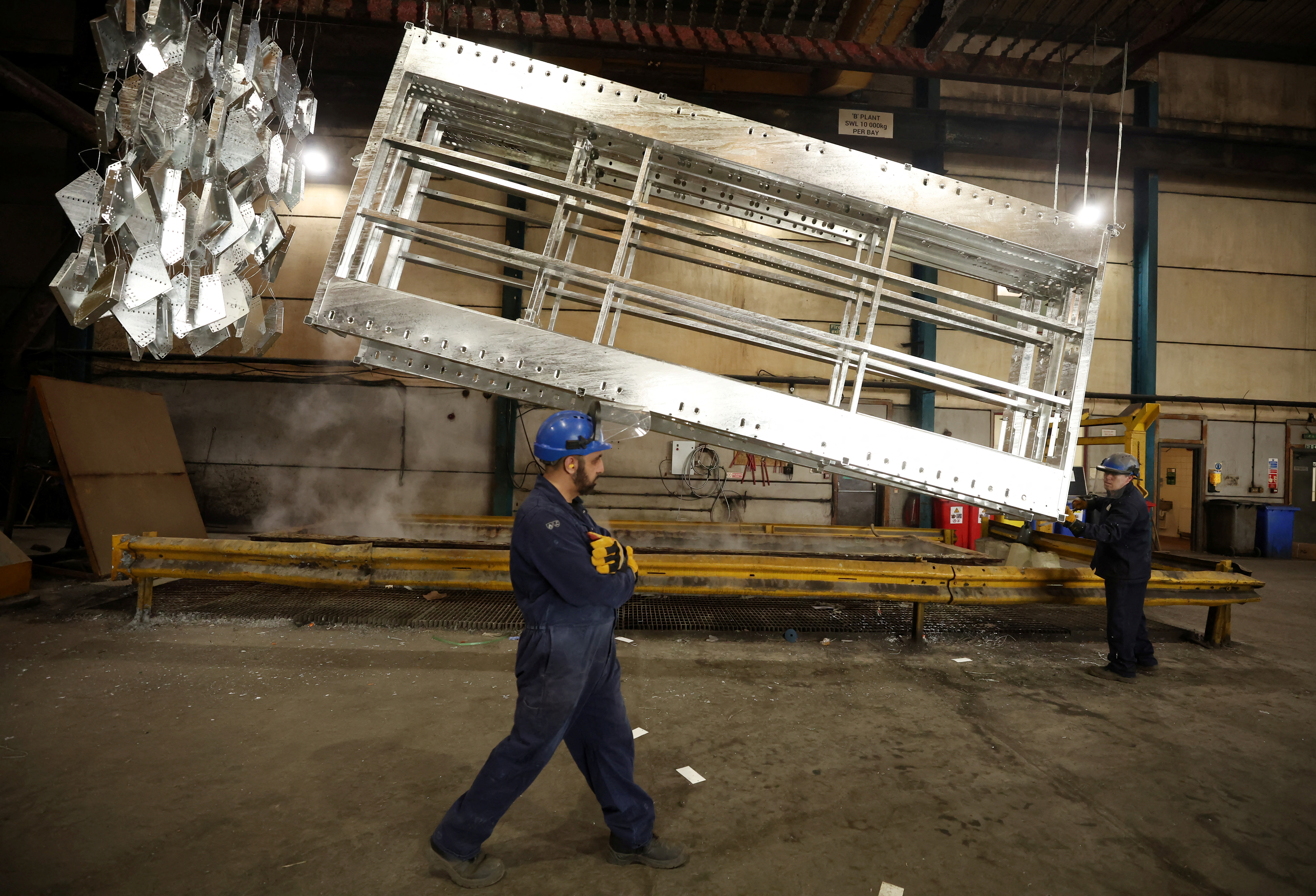 Worker walks past freshly galvanised pieces of metal inside the factory of Corbetts The Galvanizers in Telford