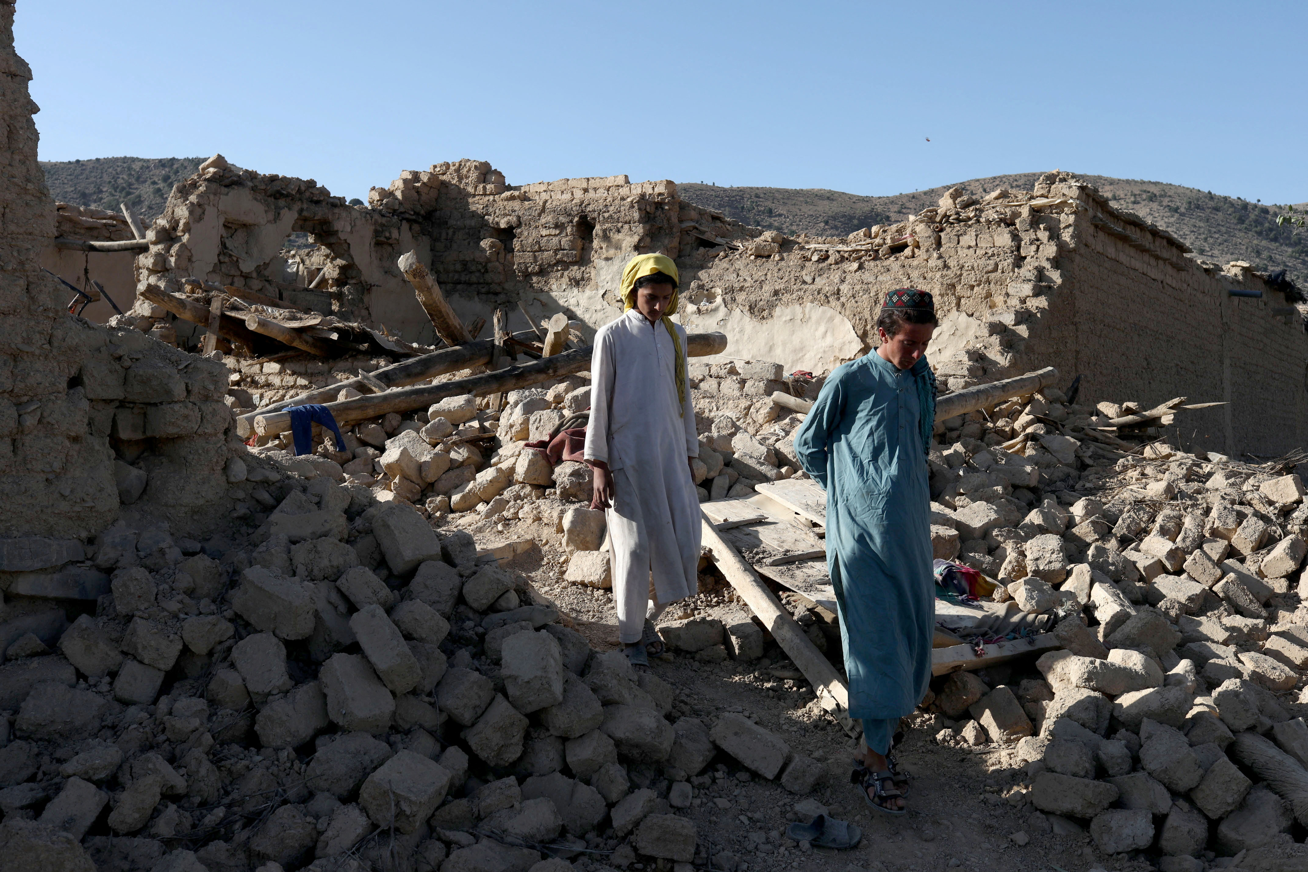 Afghans walk through the debris of damaged houses after the recent earthquake in Wor Kali village
