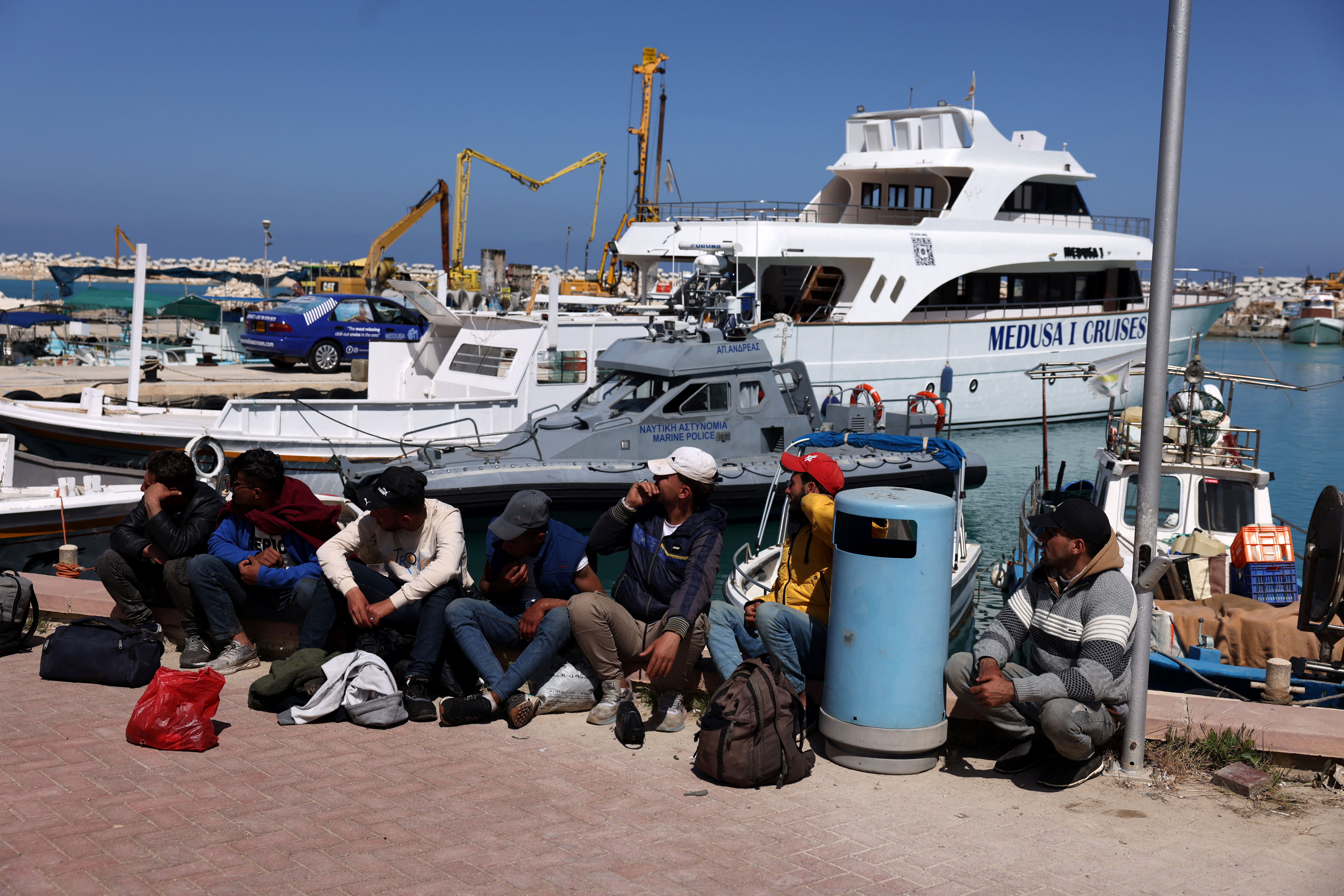 Migrants wait at a fishing shelter in Paralimni