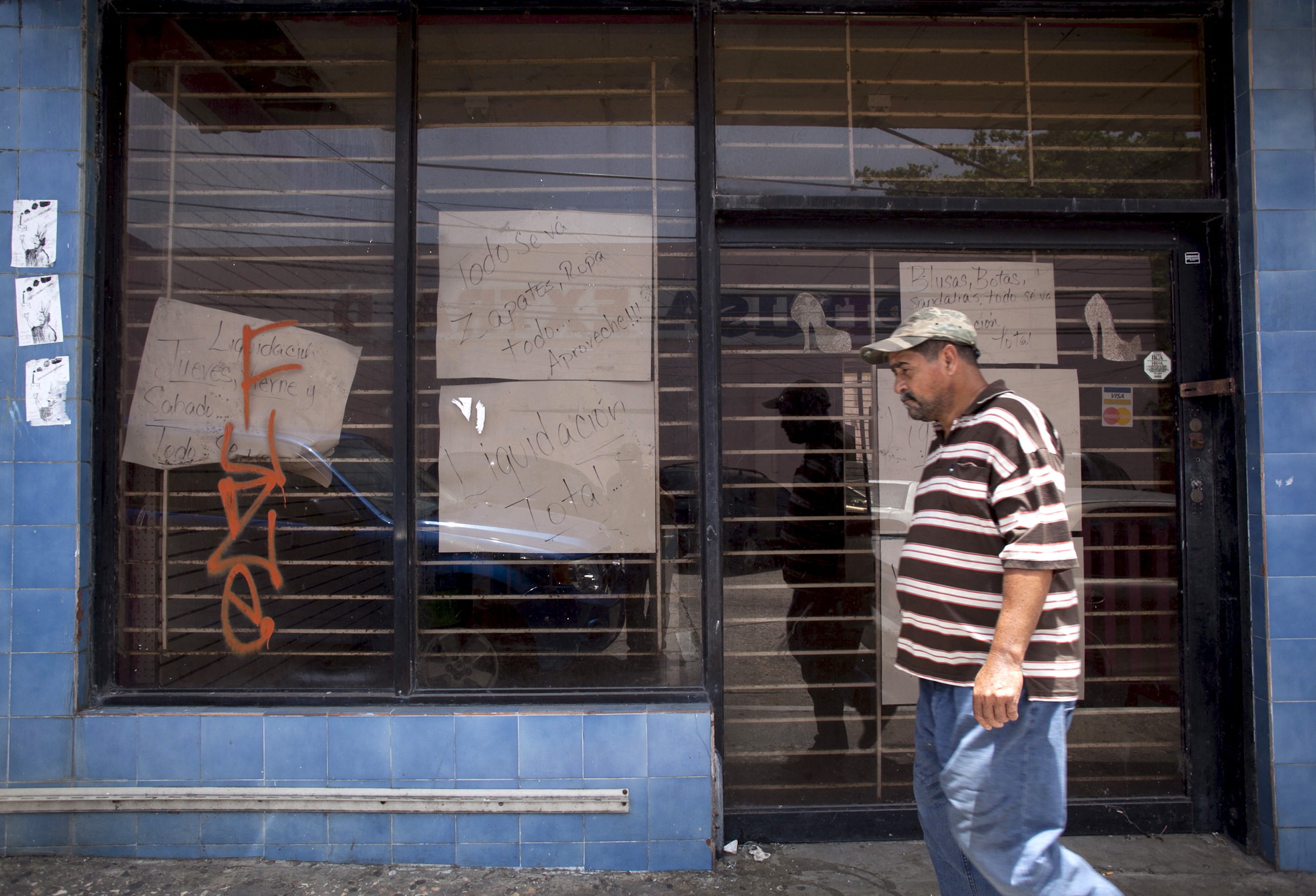 A man walks past a closed store with signs reading 