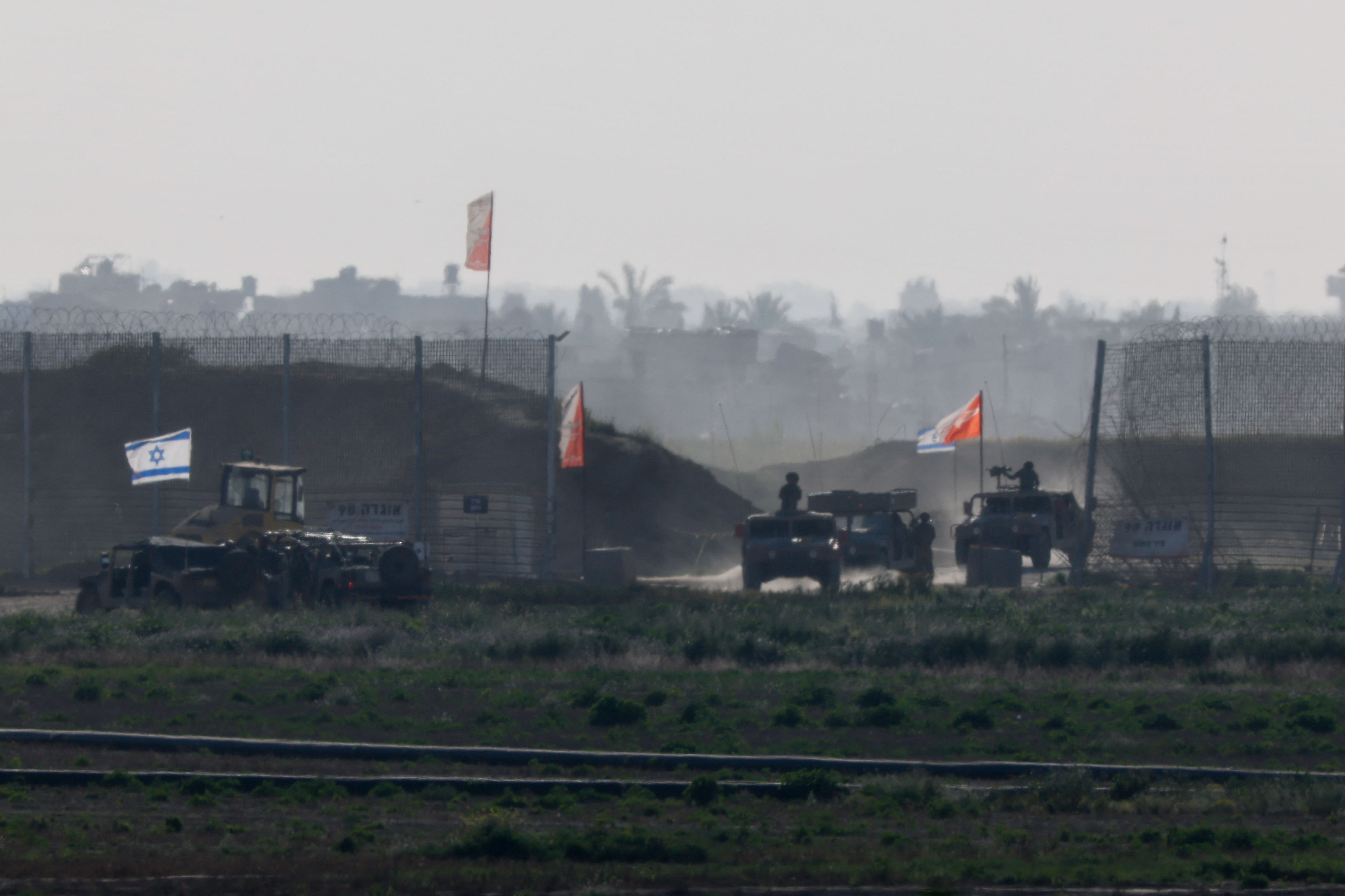 Israeli military vehicles move out from the Gaza Strip, as seen from Israel