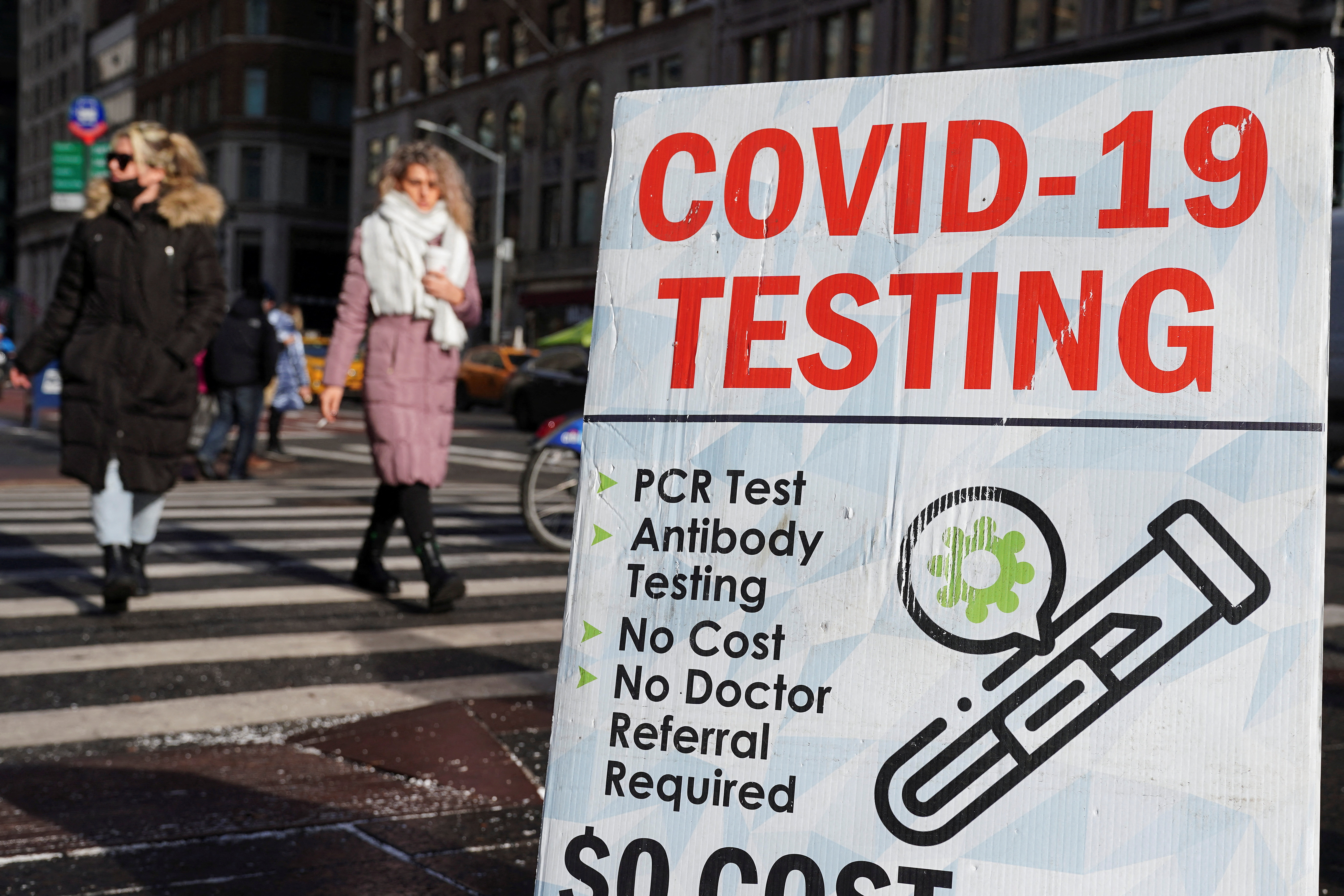 People walk past a COVID-19 testing sign during the coronavirus disease (COVID-19) pandemic in the Manhattan borough of New York City, New York, U.S., January 12, 2022.  REUTERS/Carlo Allegri