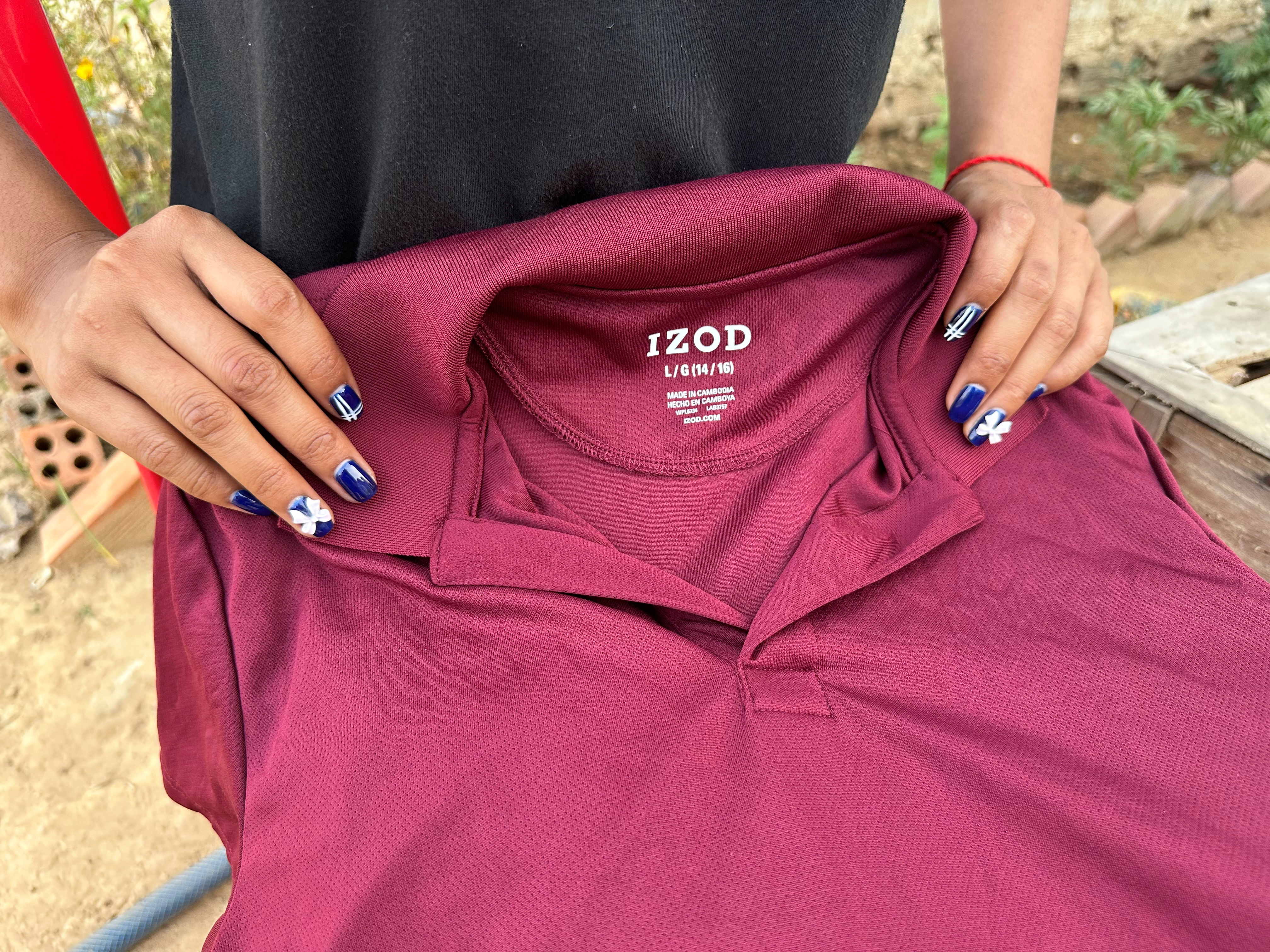 A former inmate at Correctional Center 2, a women’s prison on the outskirts of Phnom Penh, holds a polo shirt with an IZOD label that she said was made in a factory on prison grounds, at an undisclosed location in Cambodia