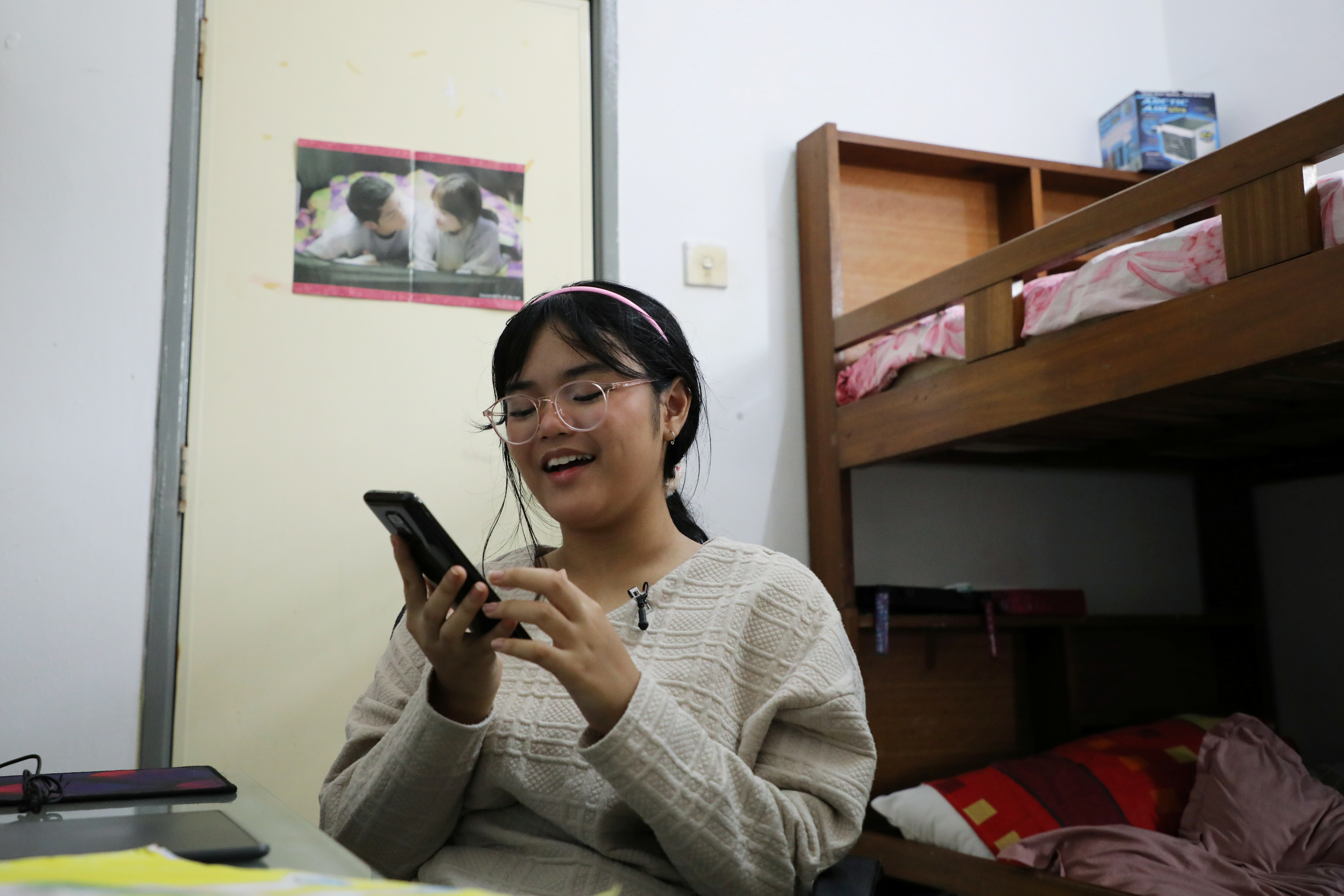 Malaysian teenager Ain Husniza Saiful Nizam uses her phone to check on the comments towards her TikTok video in her bedroom in Kuala Selangor