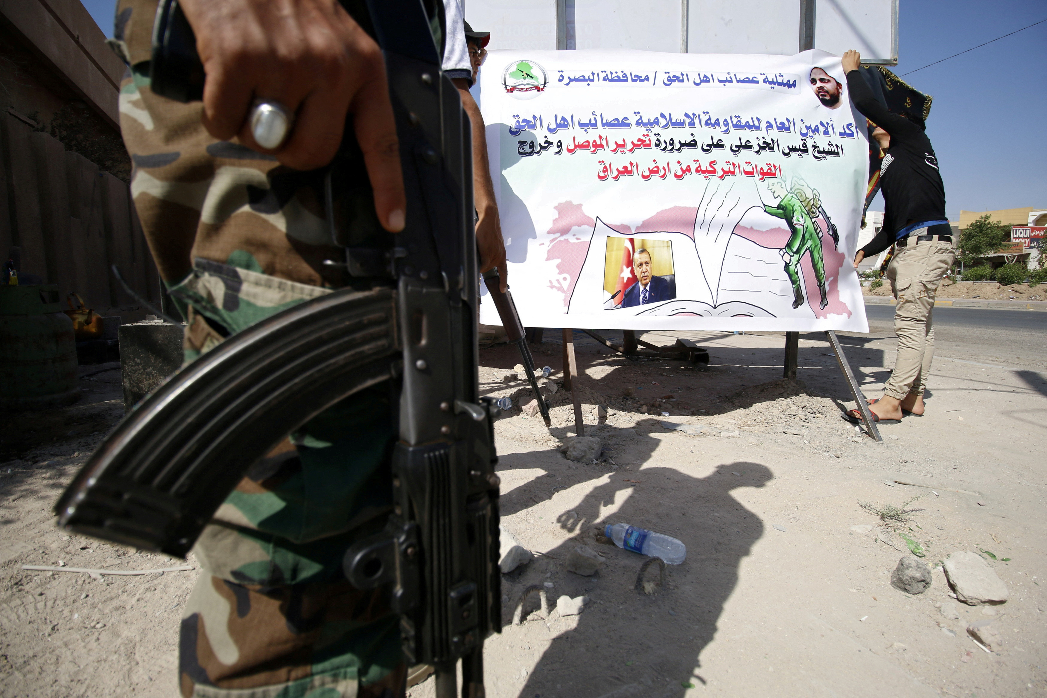 Members of Shi'ite group Asaib Ahl al-Haq put banners in the street against Turkey's military presence in Iraq, in Basra